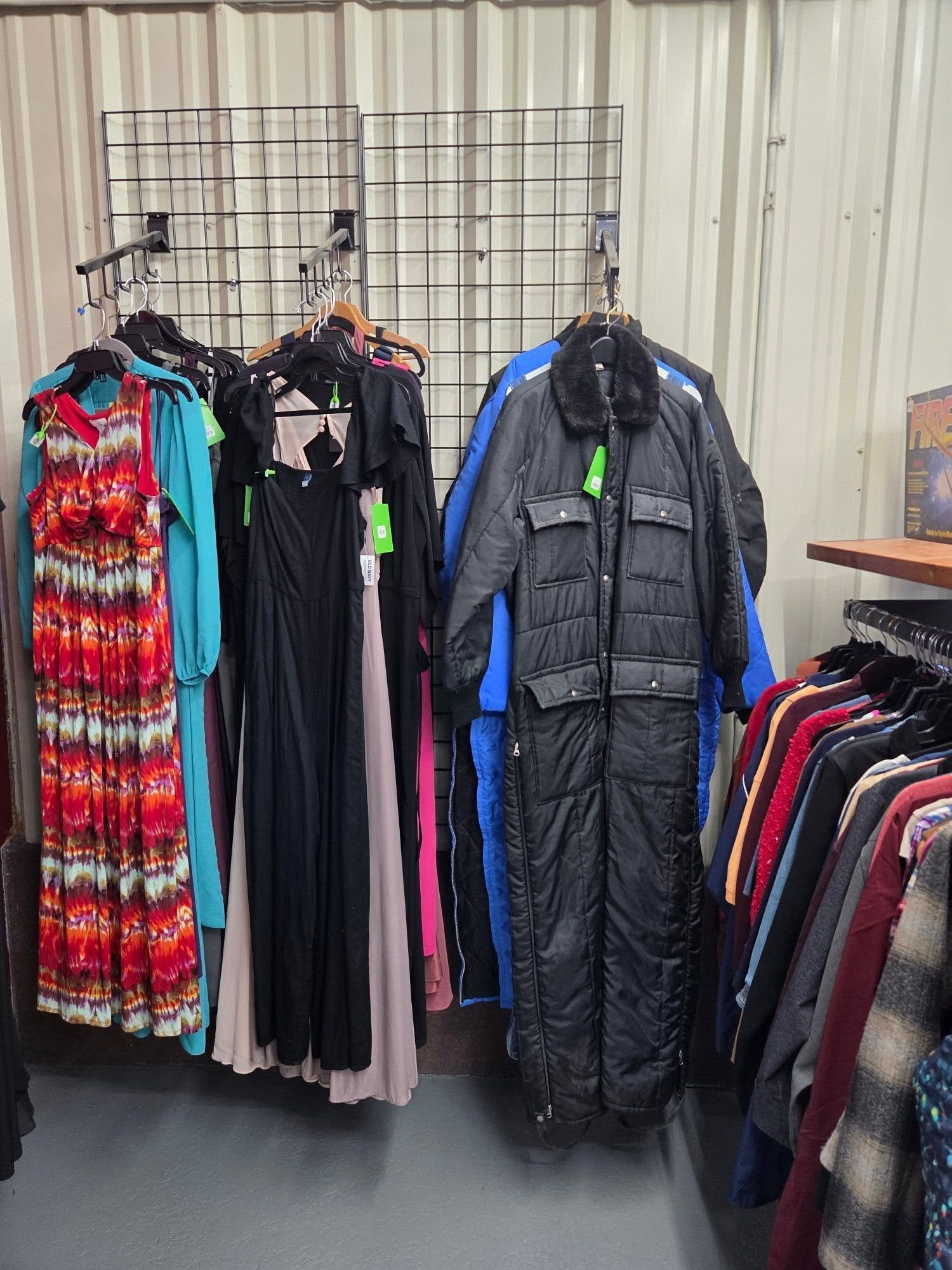 Racks of winter coats and dresses displayed outdoors at a clothing sale