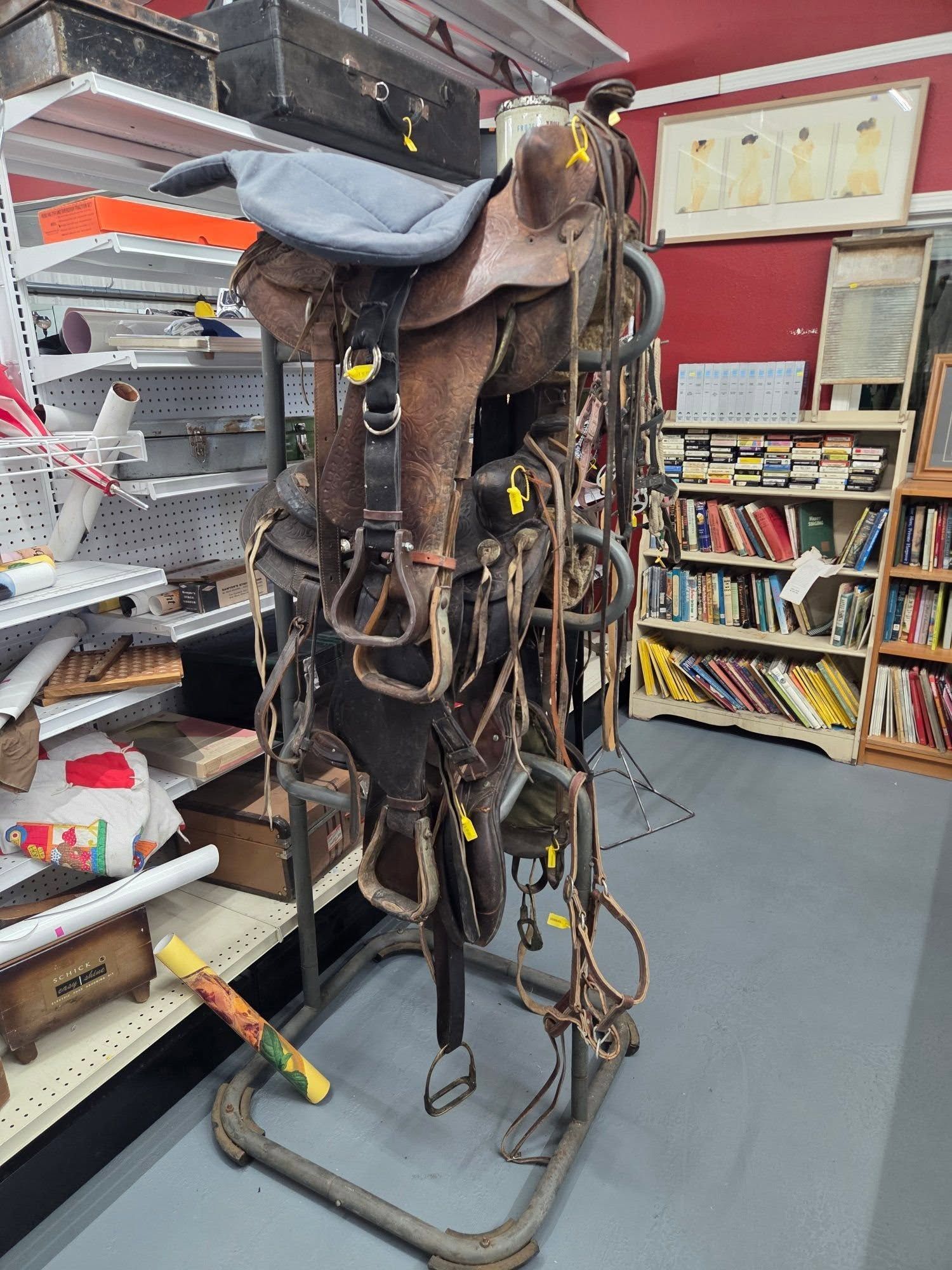 Rusty brown horse saddle and tack on a stand in a shop aisle with shelves behind it