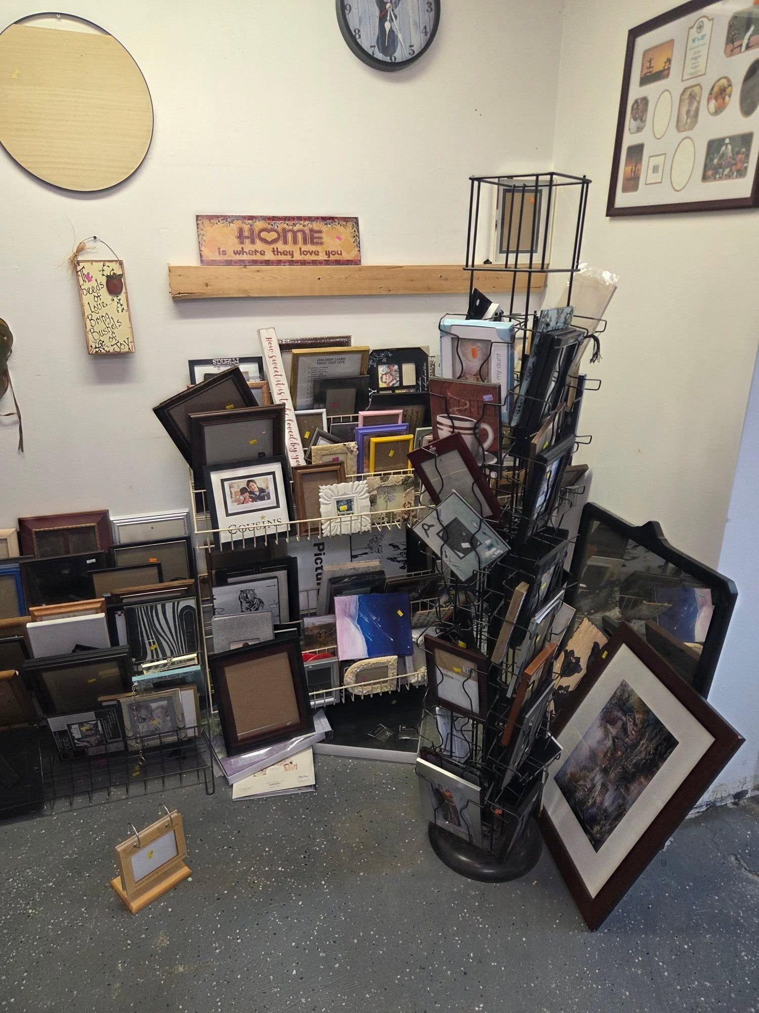 Display of many framed photos and art pieces arranged on a shelf and floor in a room
