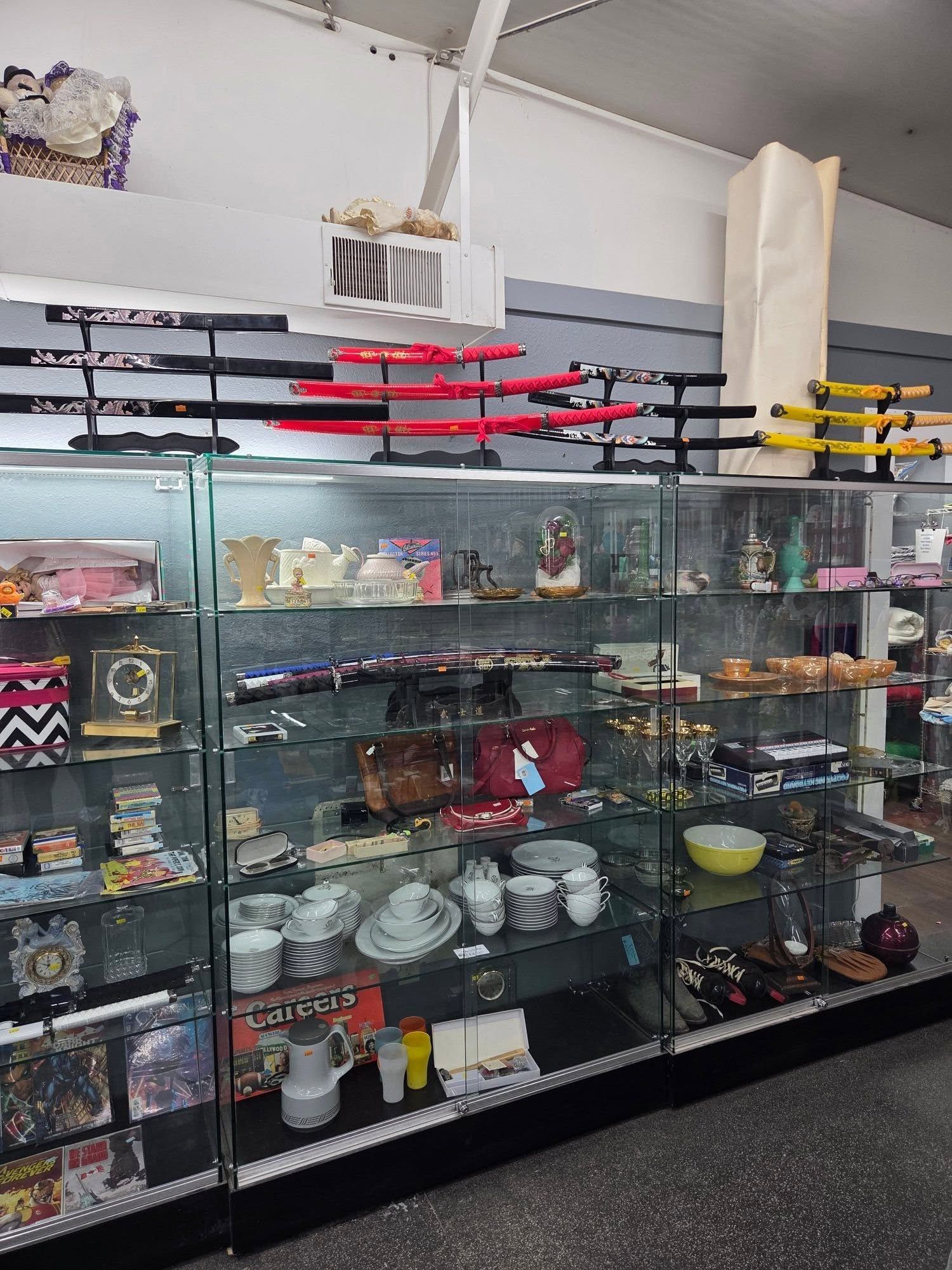 Glass display shelves with assorted bowls, plates, and home decor in a store interior