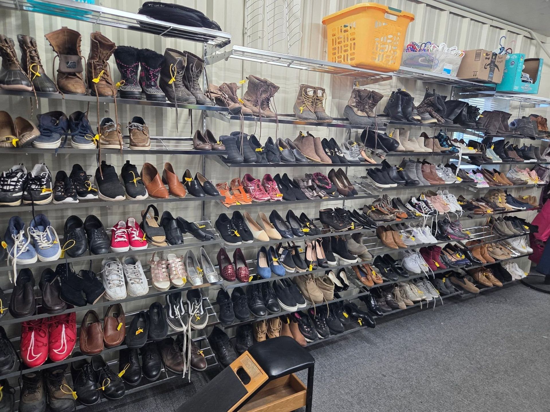 Rows of assorted used shoes on wall shelves in a thrift store aisle