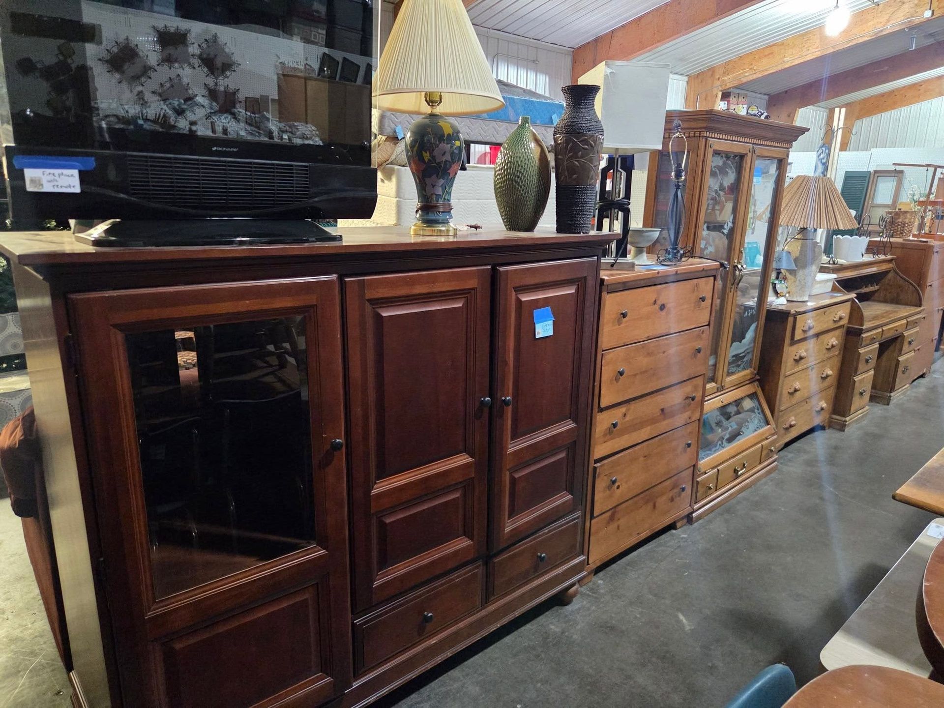 Row of wooden furniture and cabinets in an antique shop aisle