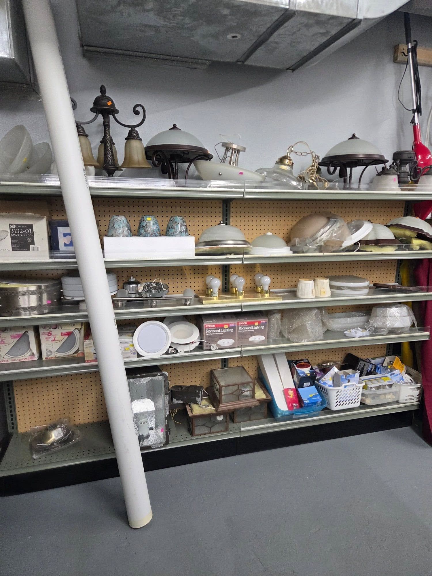 Shelves in a storage room filled with dishes, glassware, and kitchen equipment