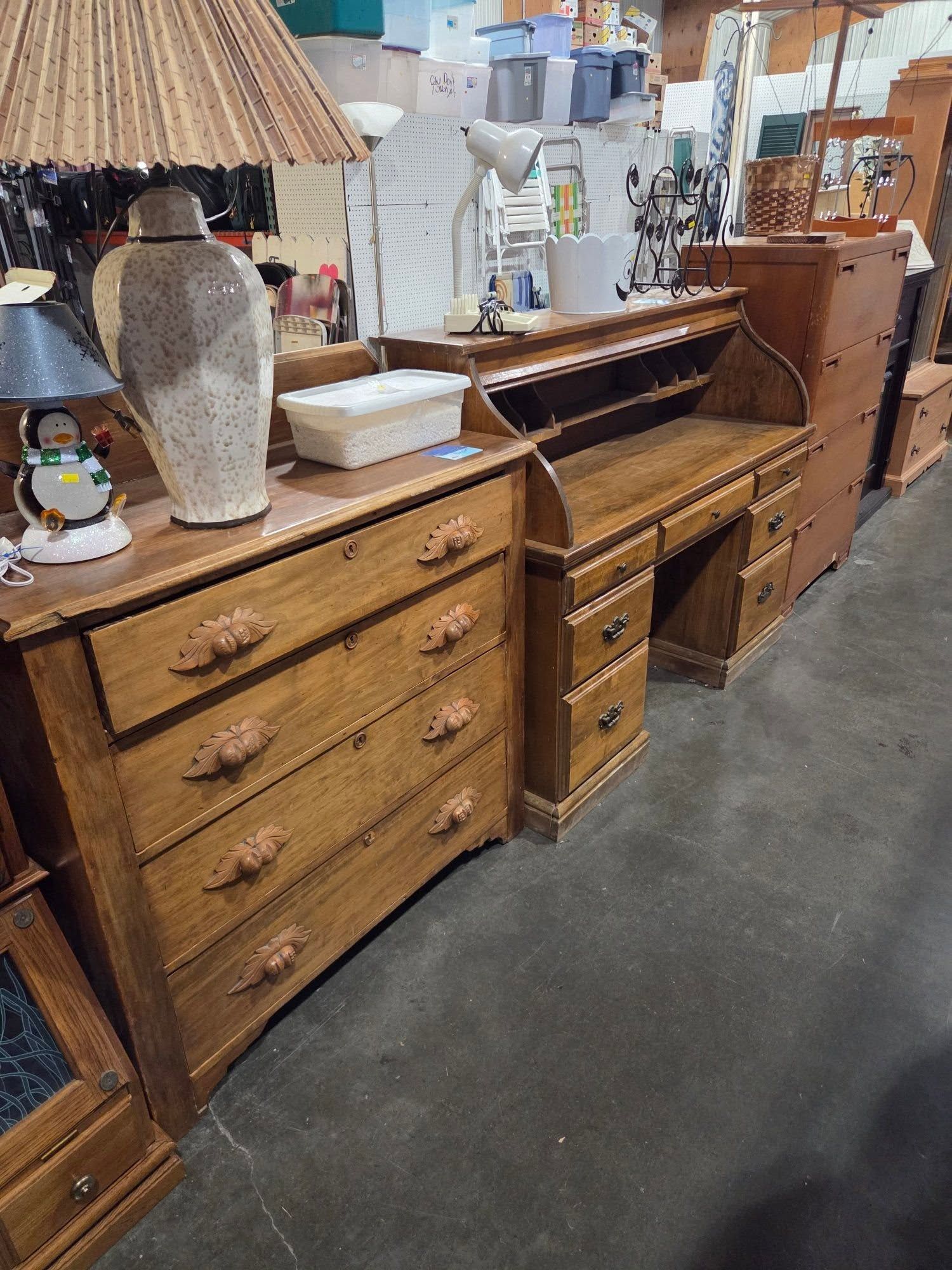 Antique wooden dressers and a piano displayed in a furniture store aisle
