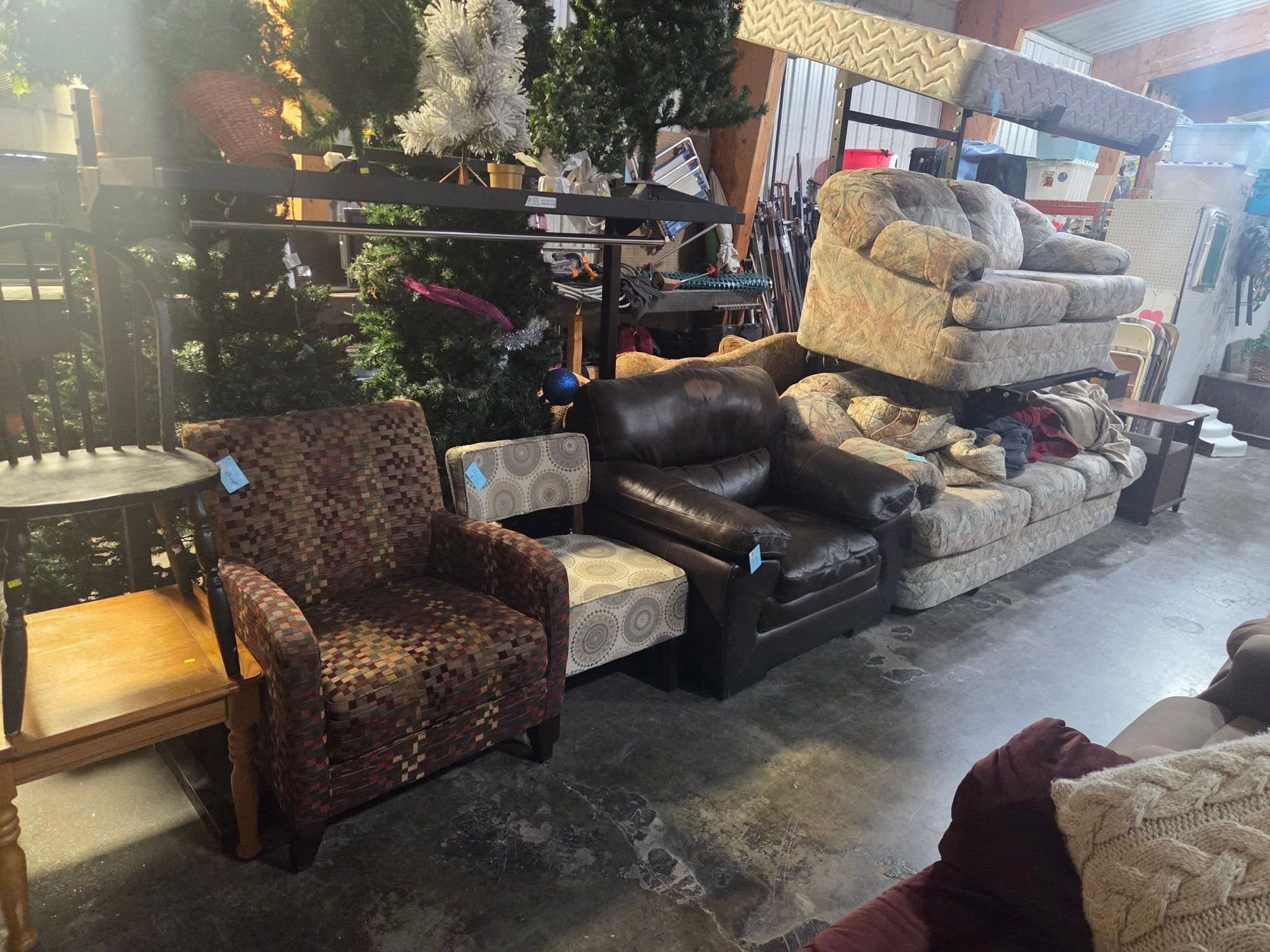 Assorted used furniture and cushions displayed in a showroom, including armchairs, sofas, and decorative items.