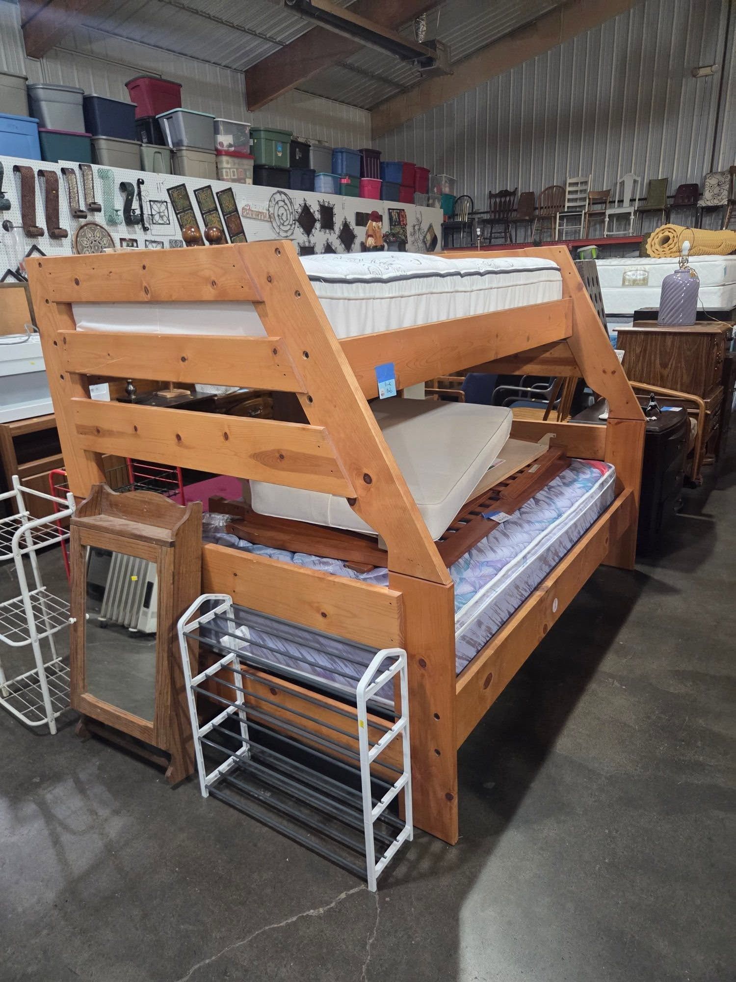 Wooden bunk bed frame with mattresses in a warehouse store aisle