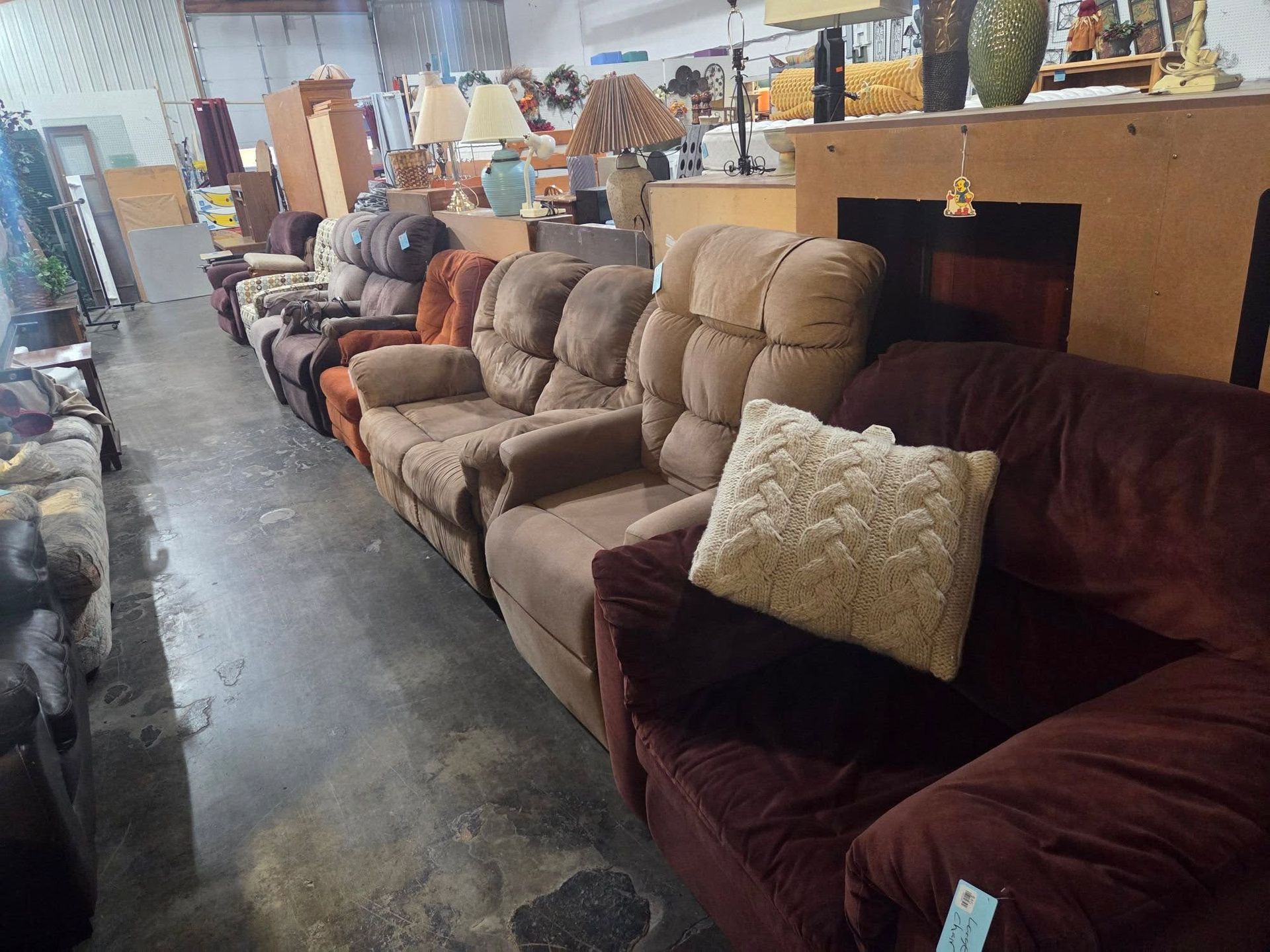 Row of upholstered recliners and sofas in a furniture showroom with polished concrete floor