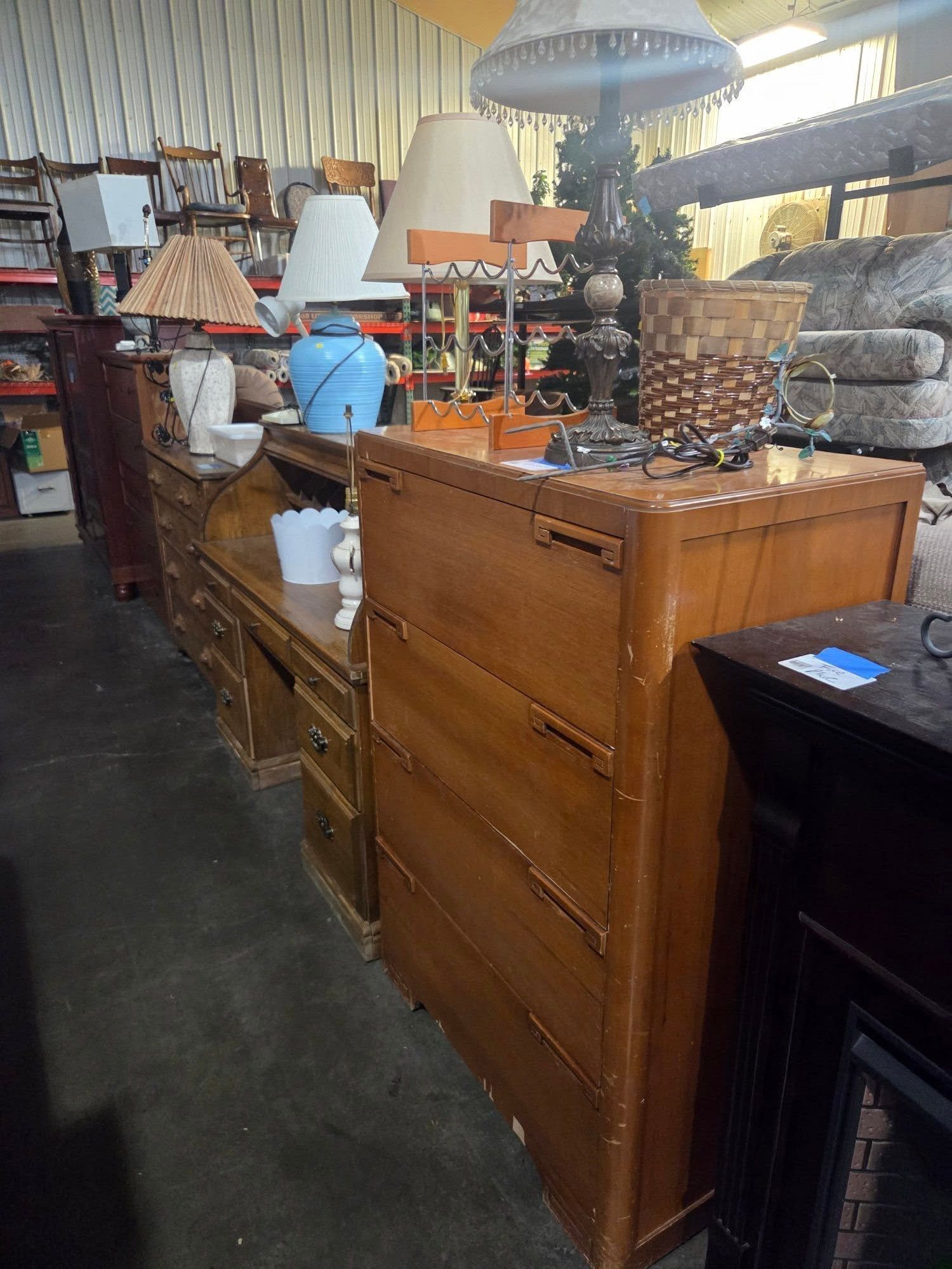 Vintage furniture store aisle with wooden cabinets, lamps, and assorted decor items