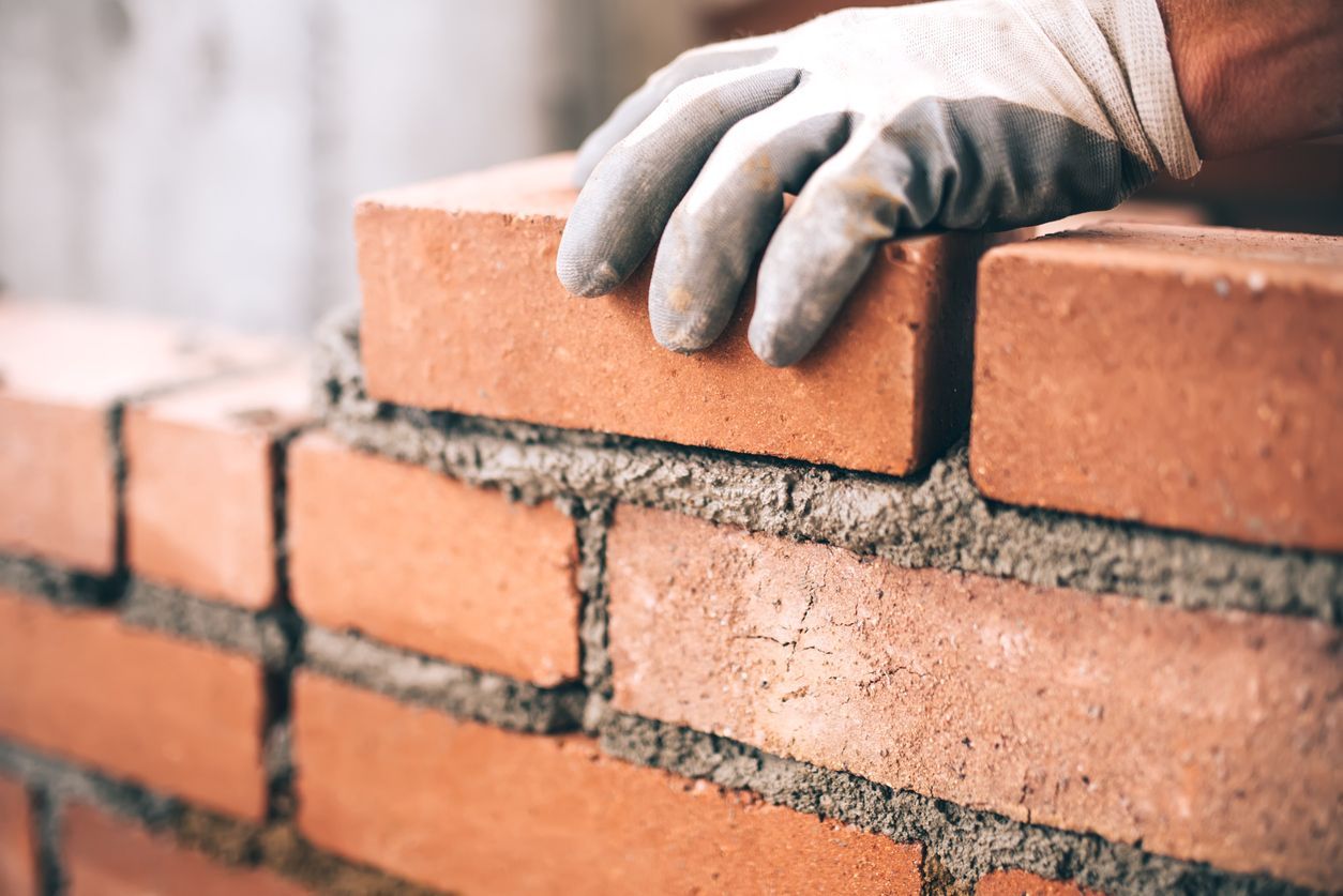 Una persona que lleva guantes está construyendo un muro de ladrillos.