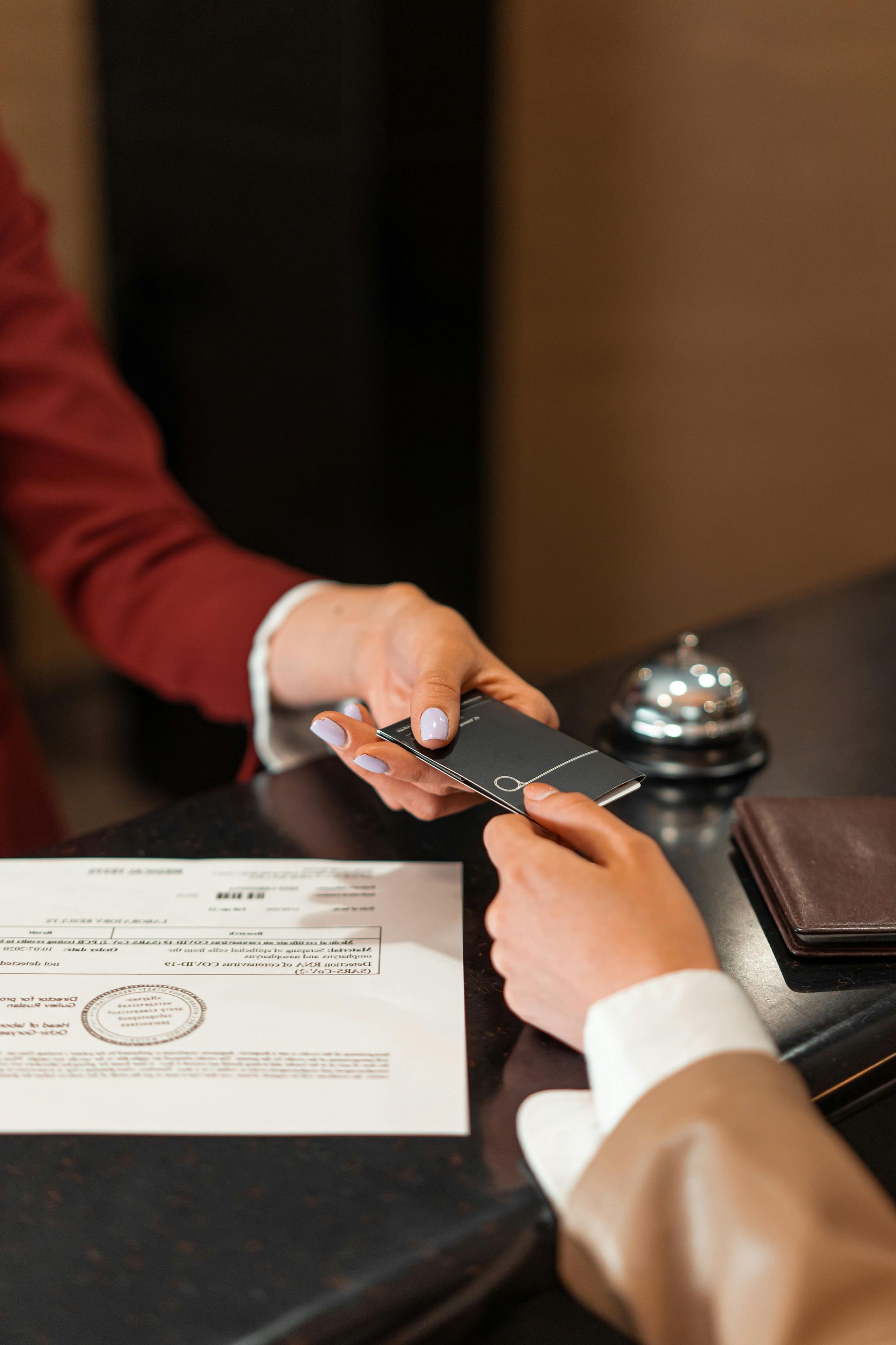 Hotel employee hands a room key to a guest at the front desk.