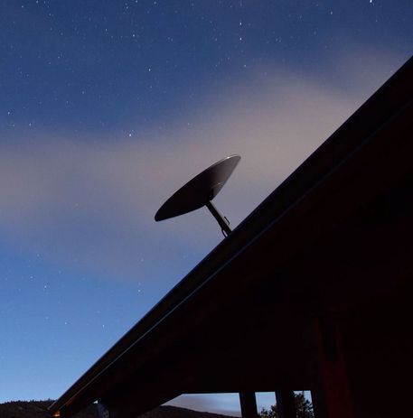 Satellite dish on a rooftop against a twilight sky — BTV Antenna & Data in Coral Cove, QLD