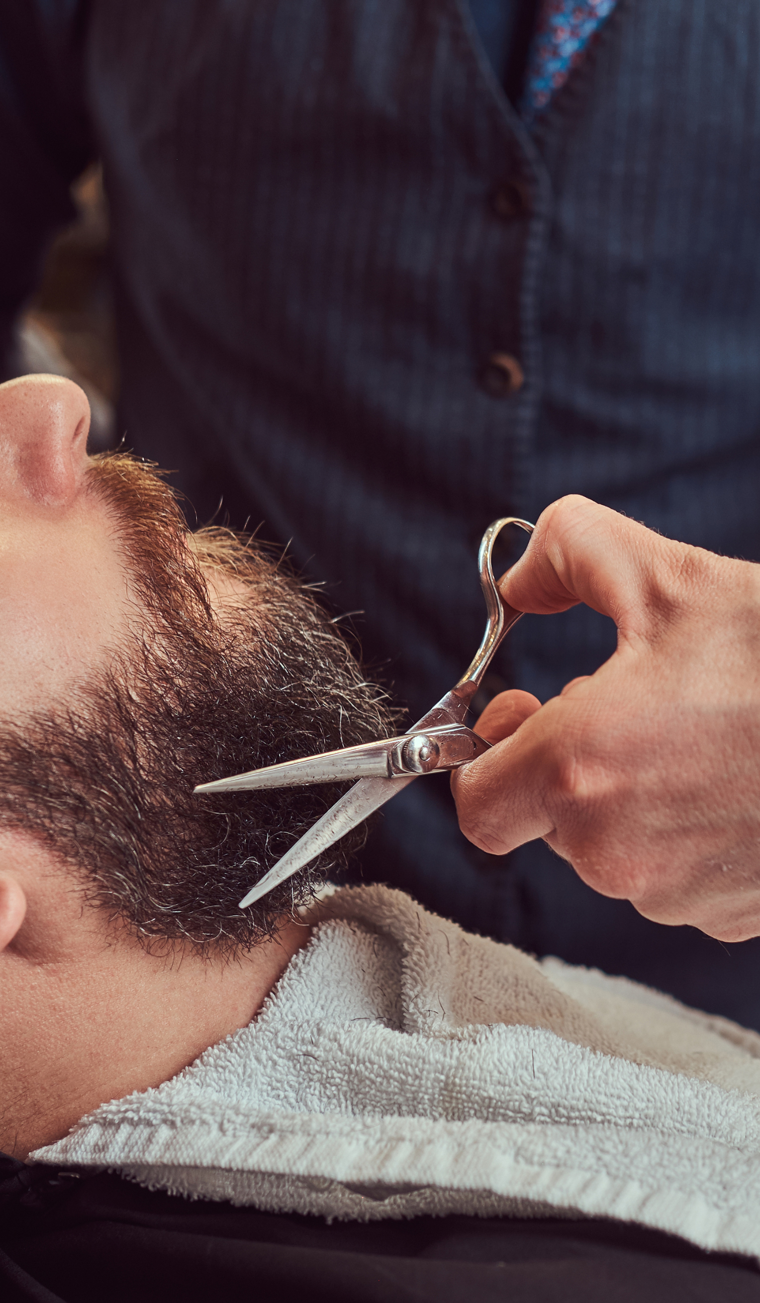 a woman is getting her hair cut by a hairdresser while holding a comb .