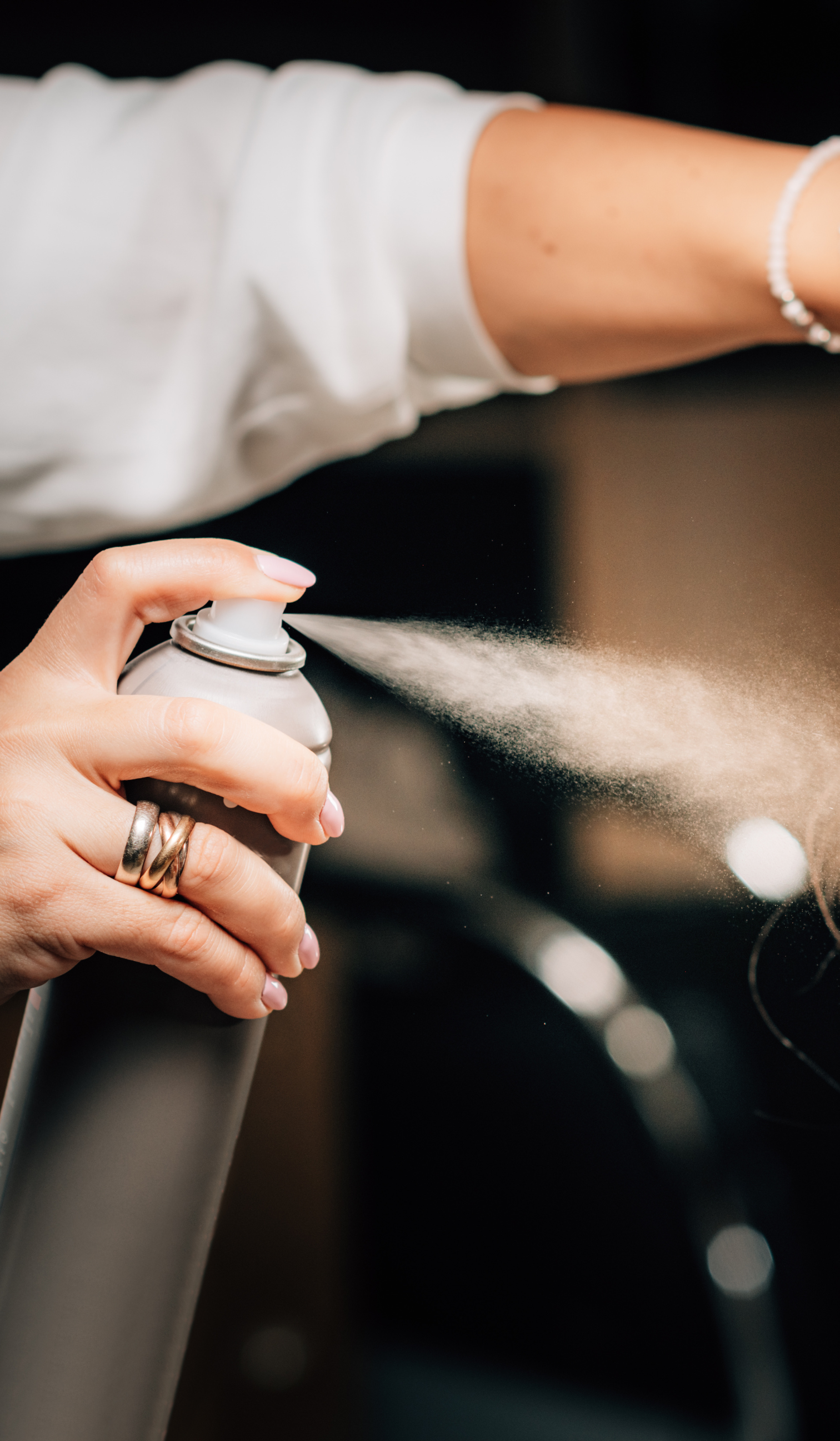 a woman is spraying her hair with a spray bottle .