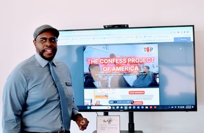a man in a suit and tie is standing in front of a large screen .
