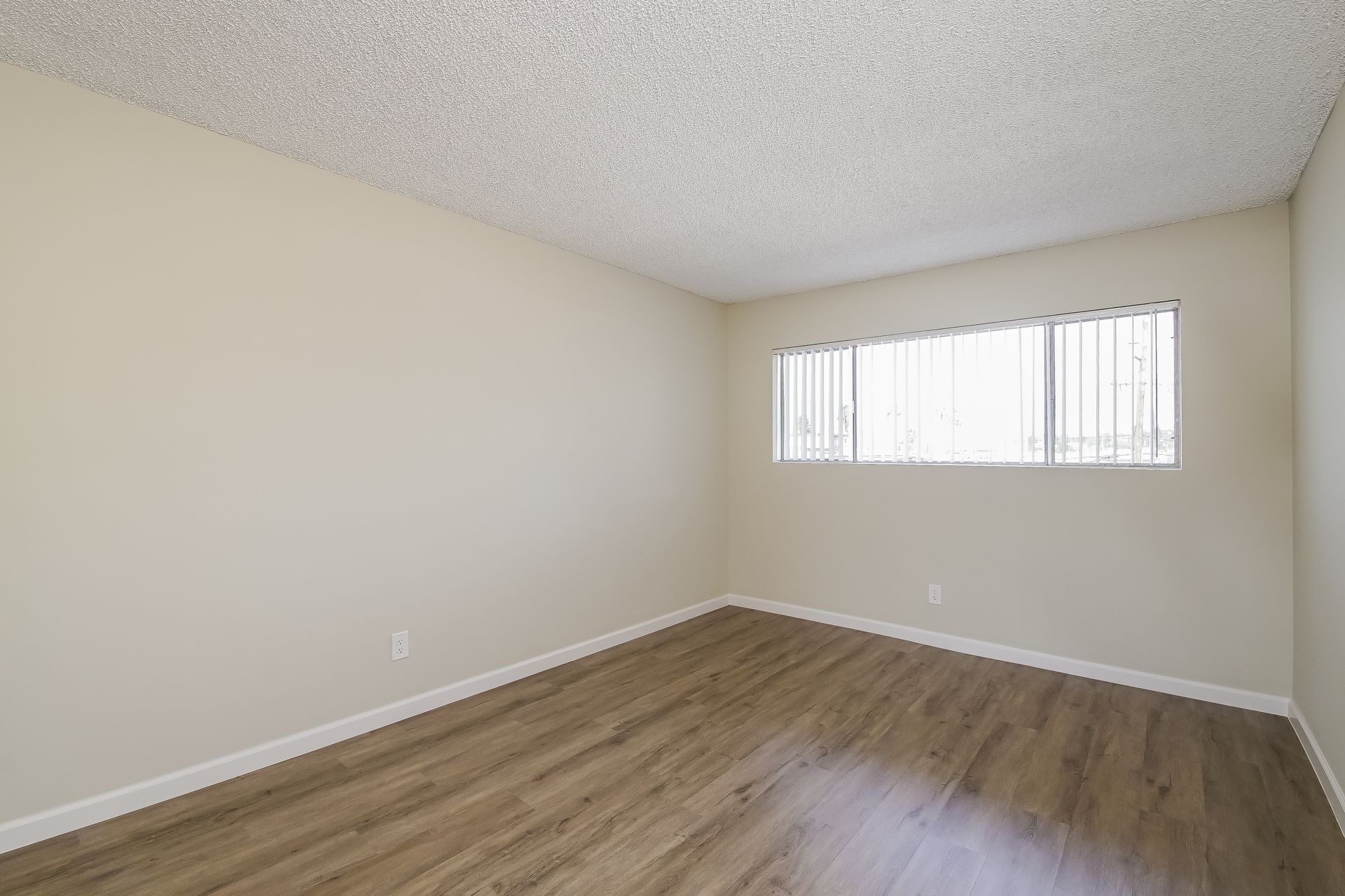 An empty room with hardwood floors and a window.