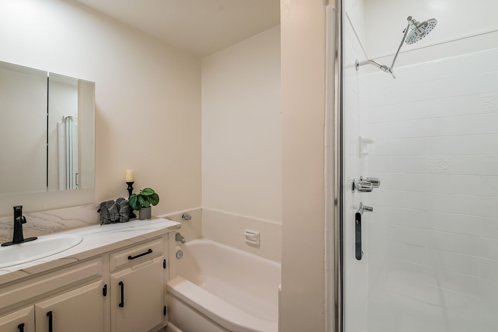 A bathroom with a tub , sink , mirror and shower.