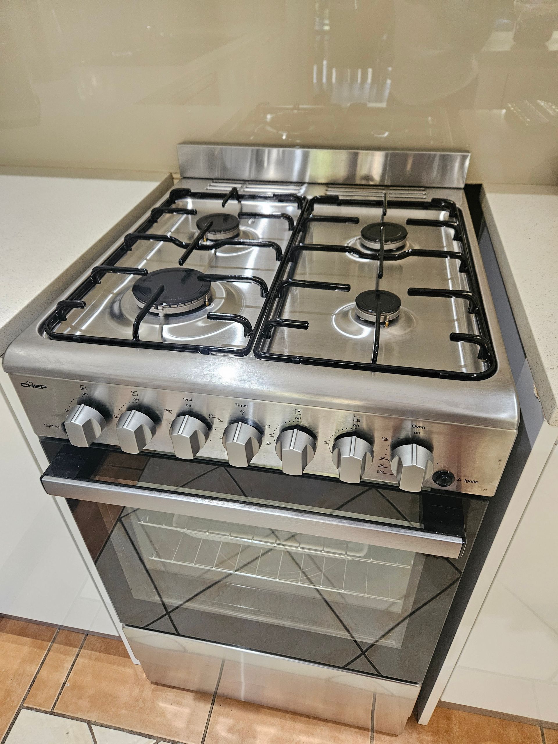 Stainless steel freestanding gas stove with oven in a kitchen, seen from the front.