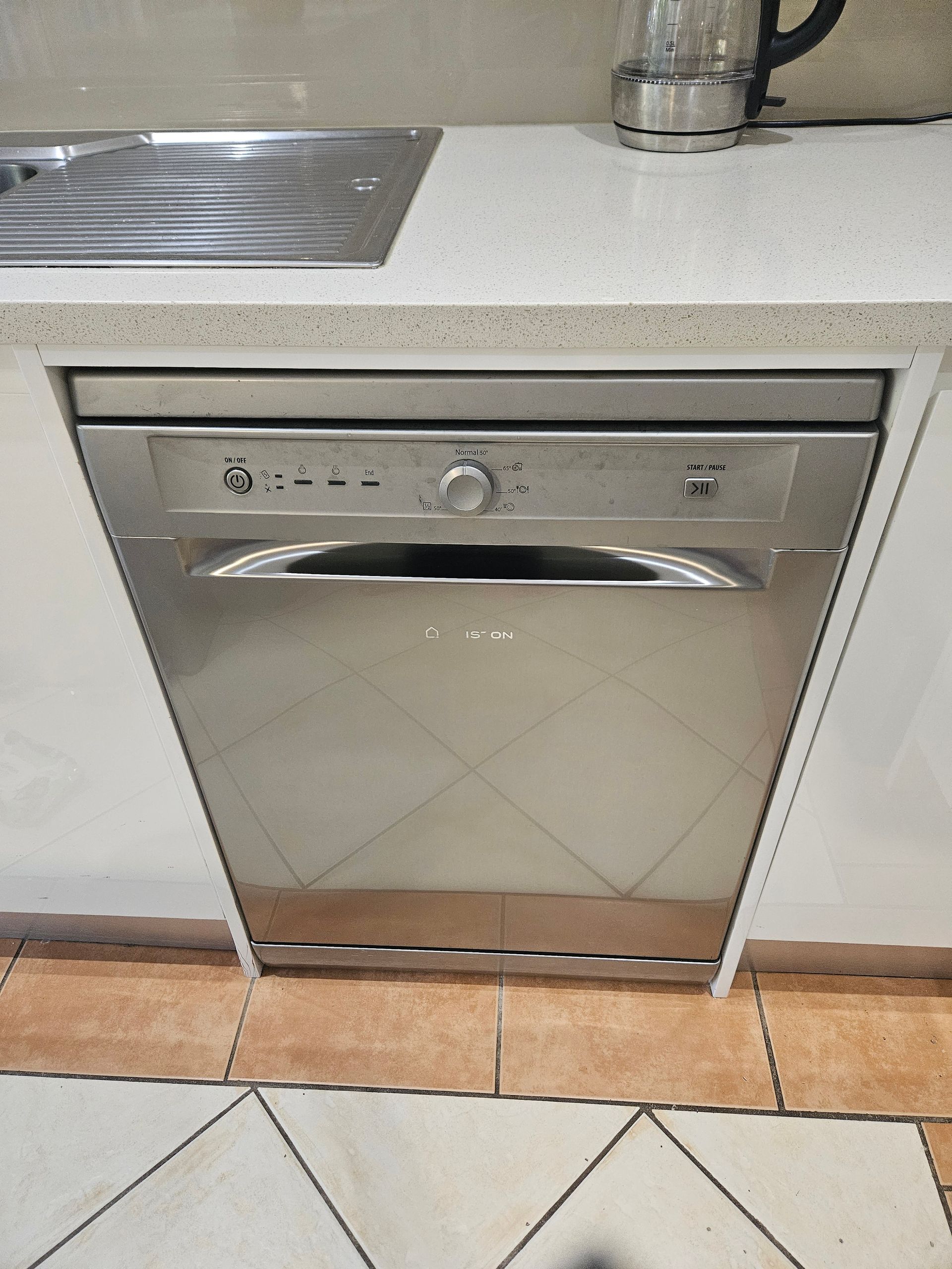 Built-in stainless steel dishwasher under a kitchen counter, with a sink beside it.