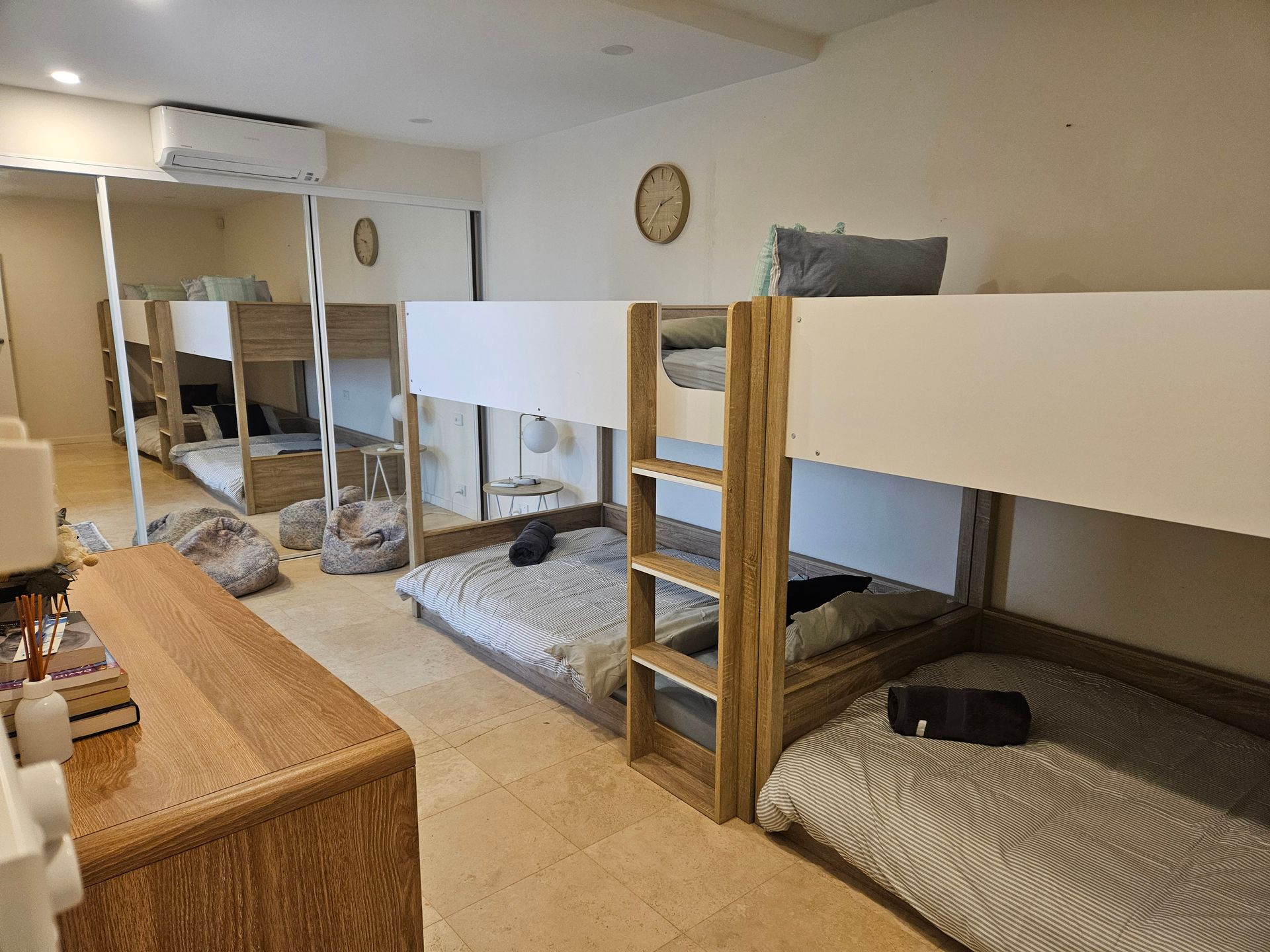 Shared bedroom with bunk beds, patterned rugs, and wood furniture in a bright dorm-style room