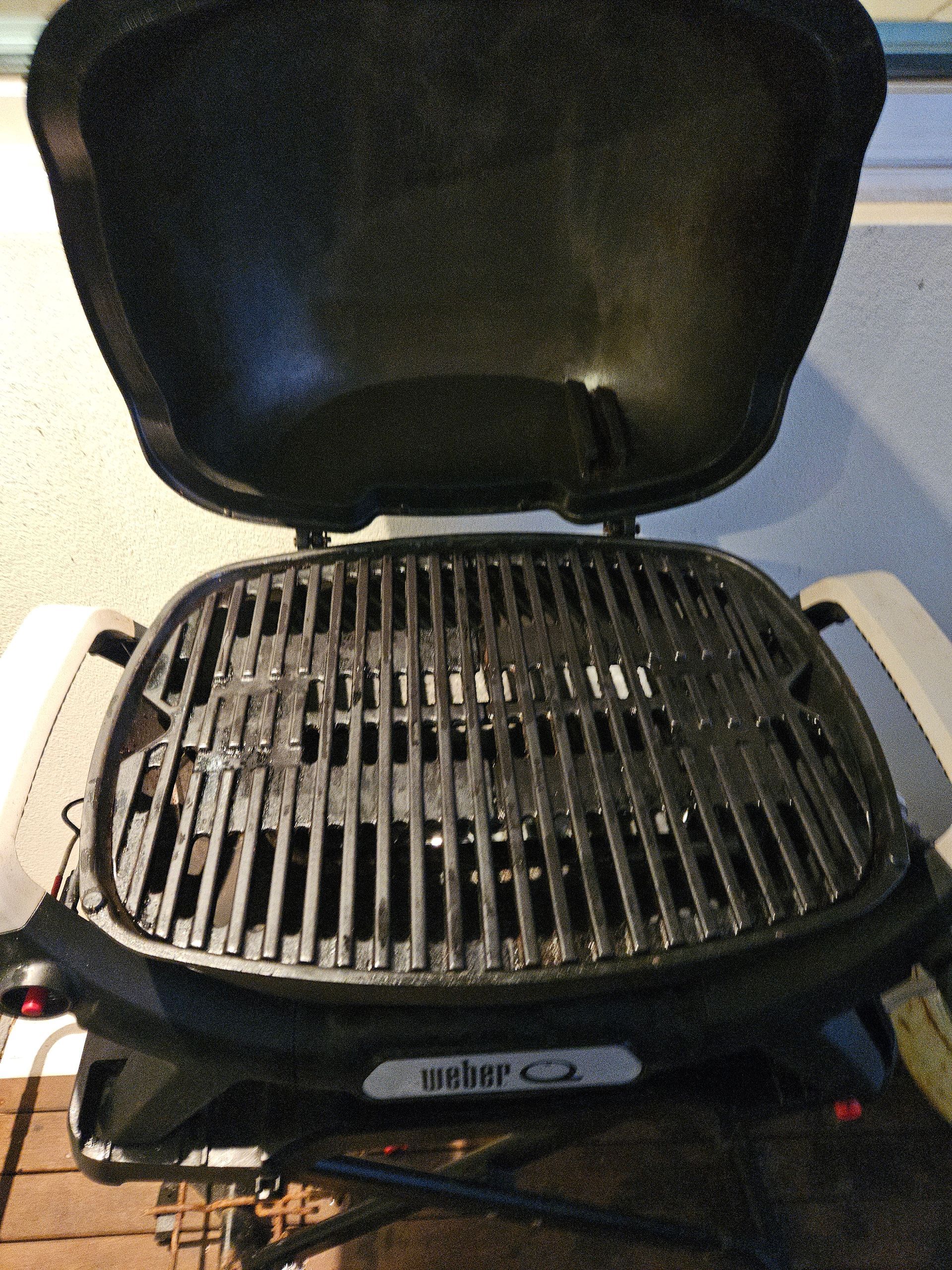 Open tabletop grill with lid raised, showing the cooking grates.