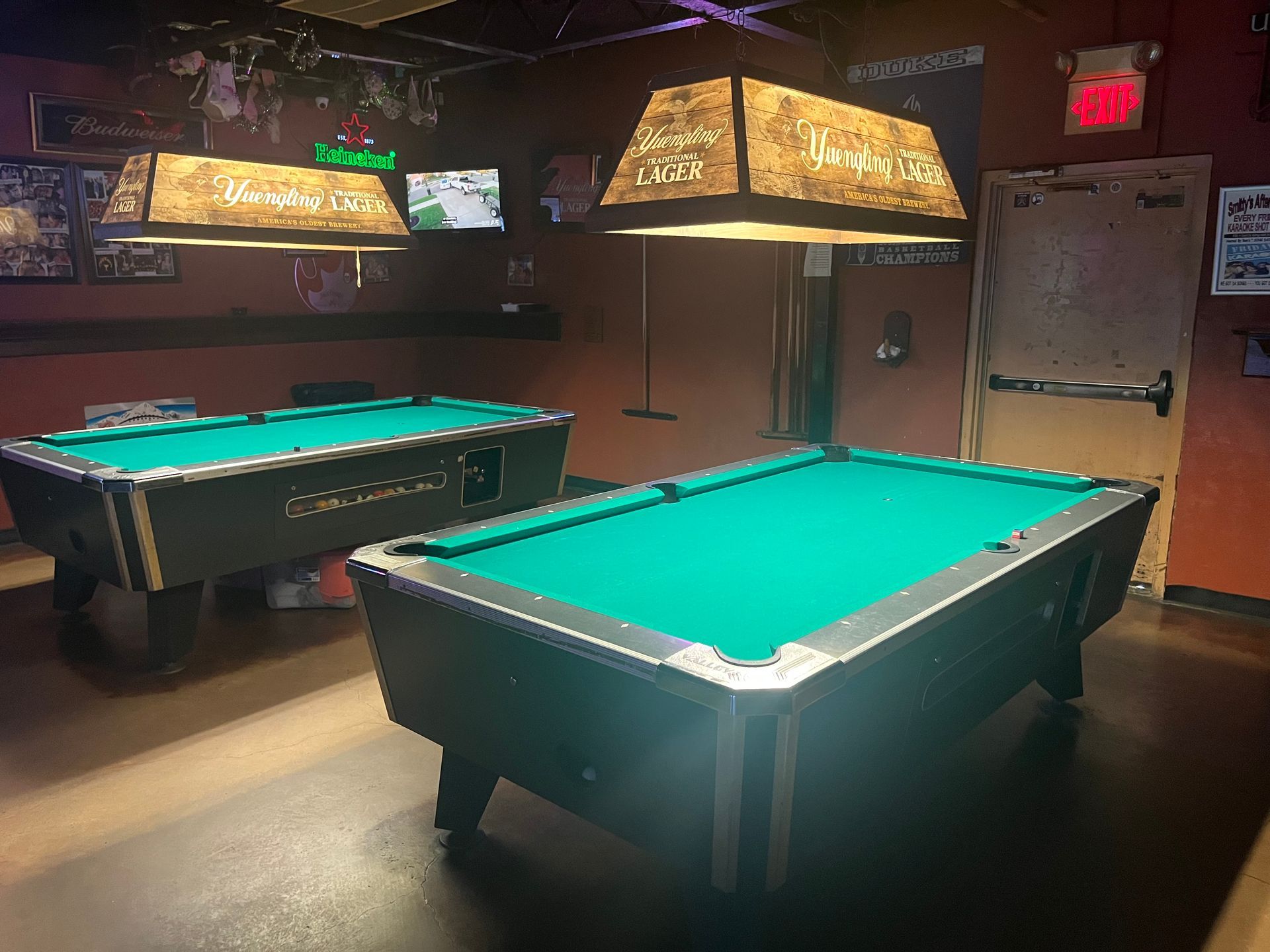 Two pool tables are sitting in a dark room.
