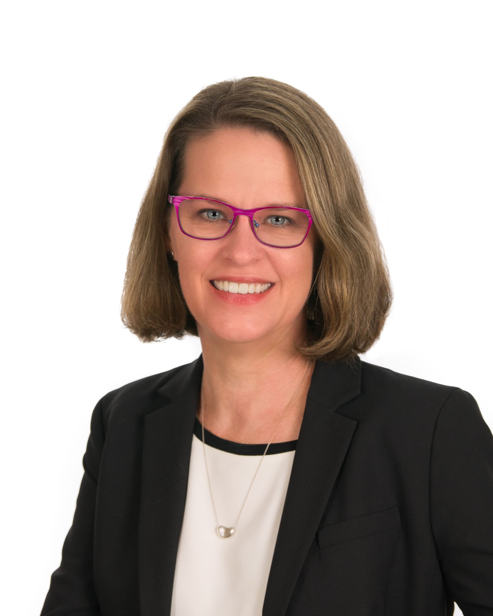 Headshot of a smiling person wearing pink glasses, a black blazer, and white top on a white background