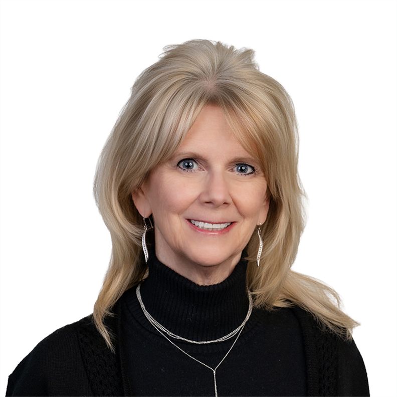Portrait of a smiling person with gray hair, glasses, and a black-and-white sweater on a white background