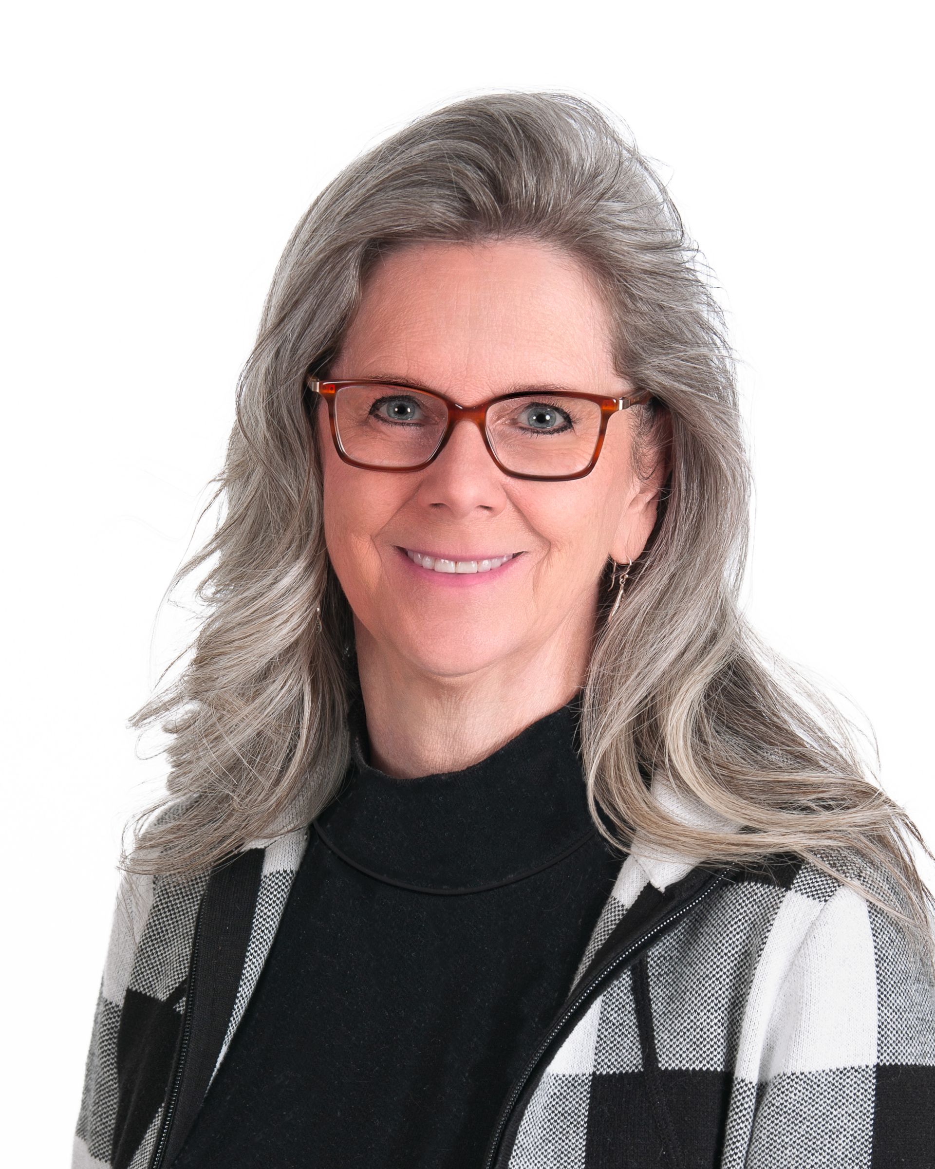 Portrait of a smiling person with gray hair, glasses, and a black-and-white sweater on a white background