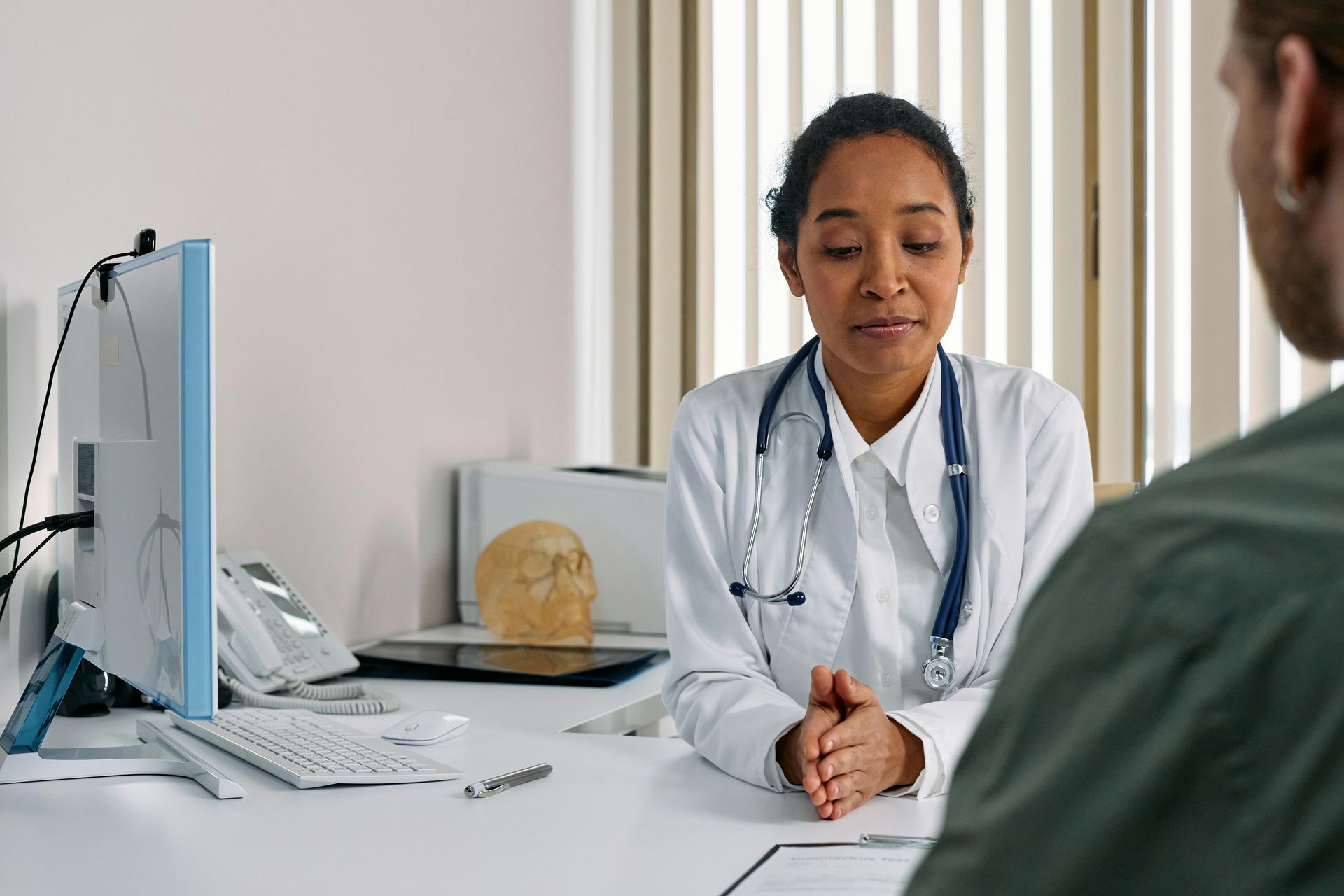 Doctor in white coat speaking with a patient in a bright clinic office