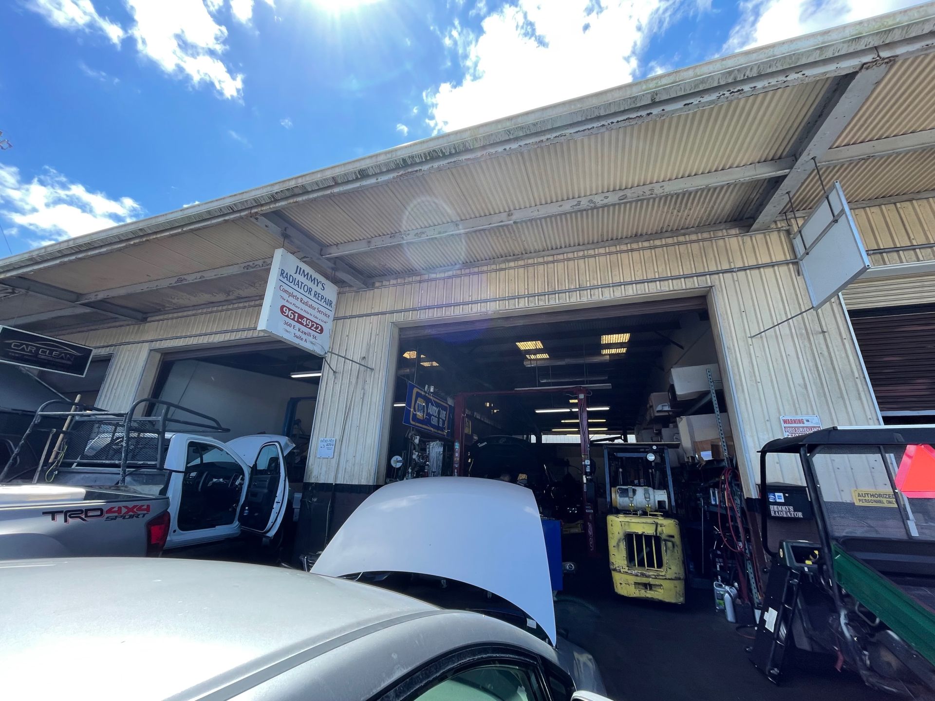 Car with open hood in front of garage