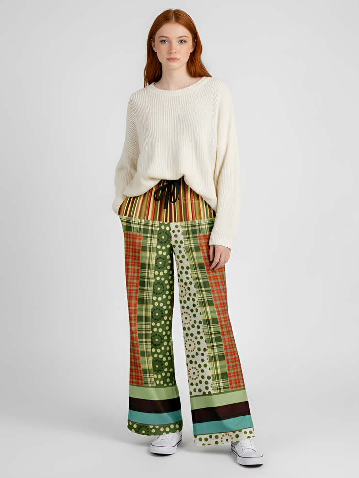Woman in cream sweater and patterned pants, standing with white sneakers on.