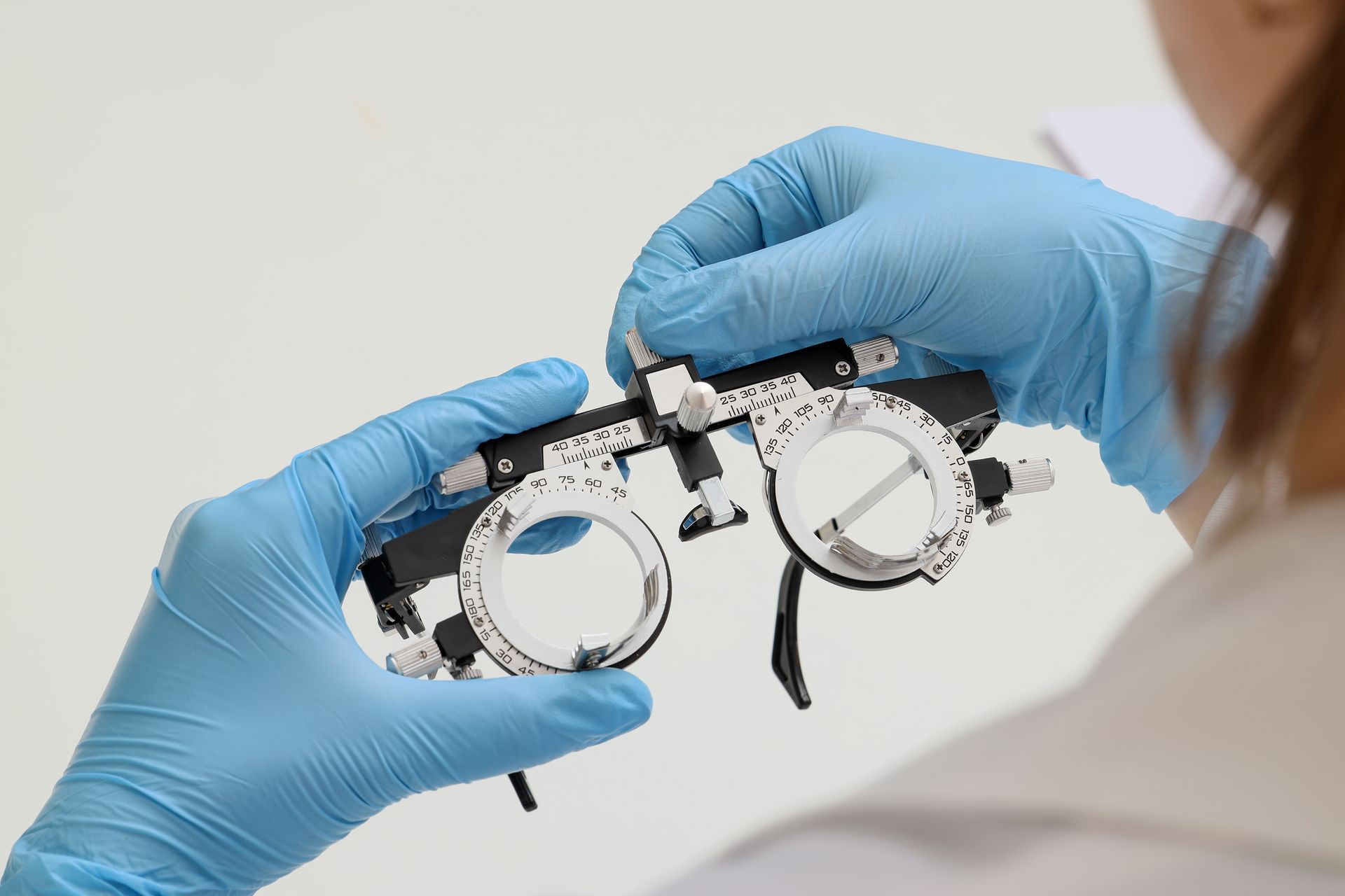 Optician holding trial frame glasses for eye exam