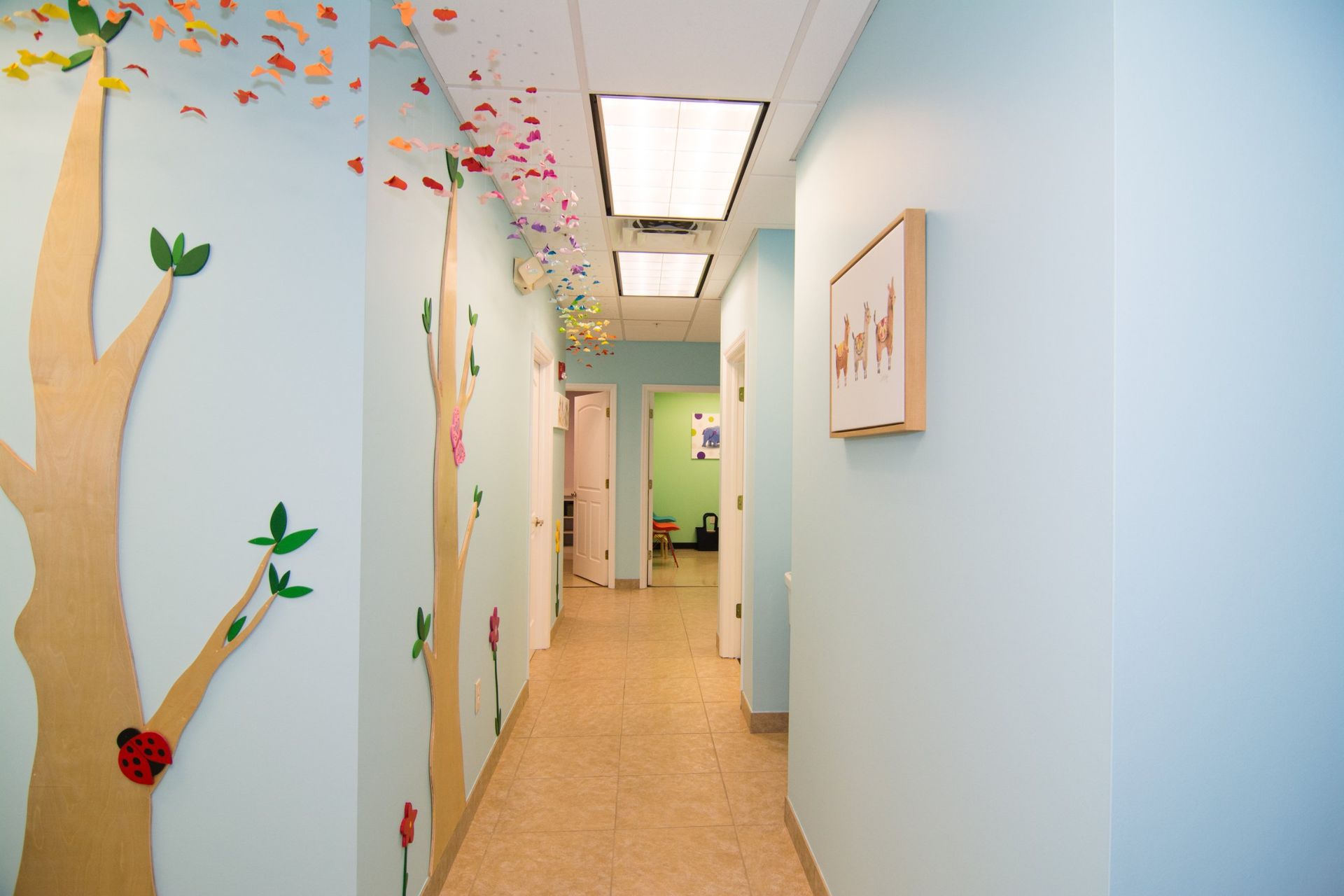 photo of the hallway showing 4 white doors, light blue walls with tree decals on the left