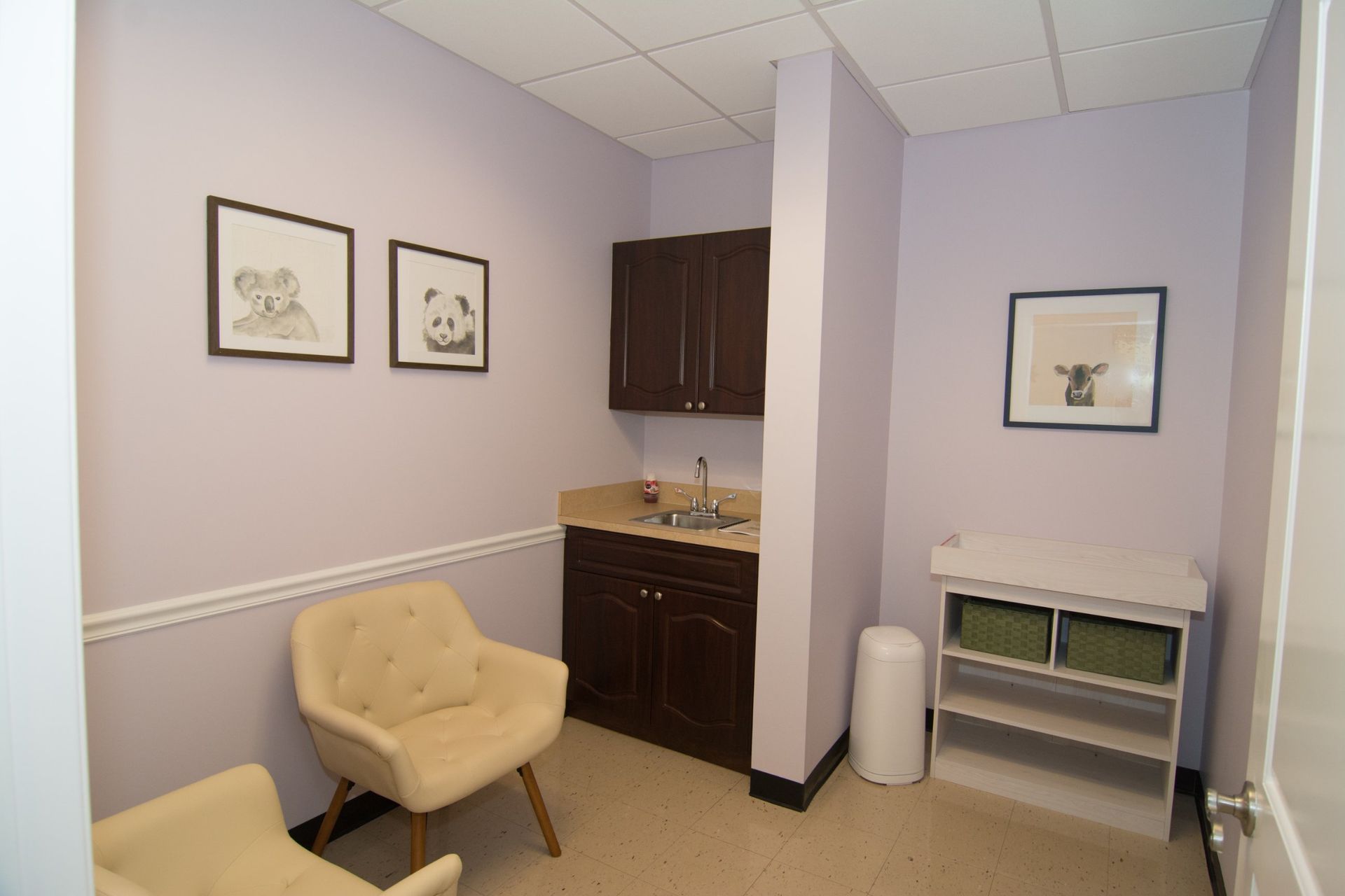 Photo of their waiting room with tow beige colored chairs beside the sink, two pencil drawn painting on the wall