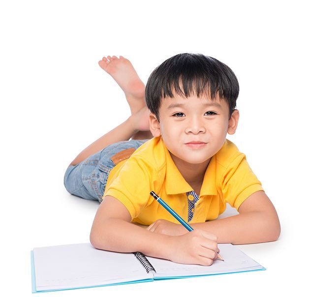 young boy doing homework laying down
