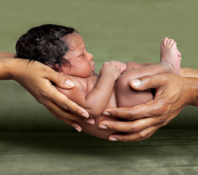 parents holding their newborn baby in the palm of their hands