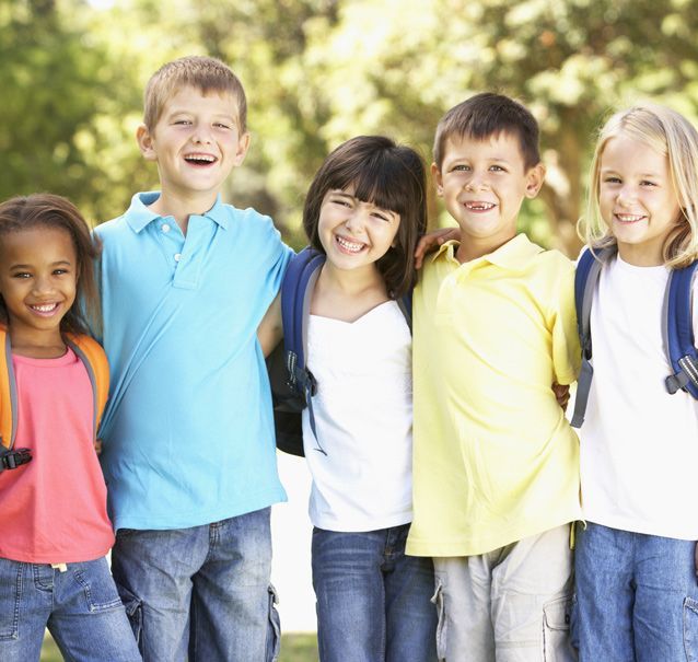 young school kids of different races standing beside each other smiling outside