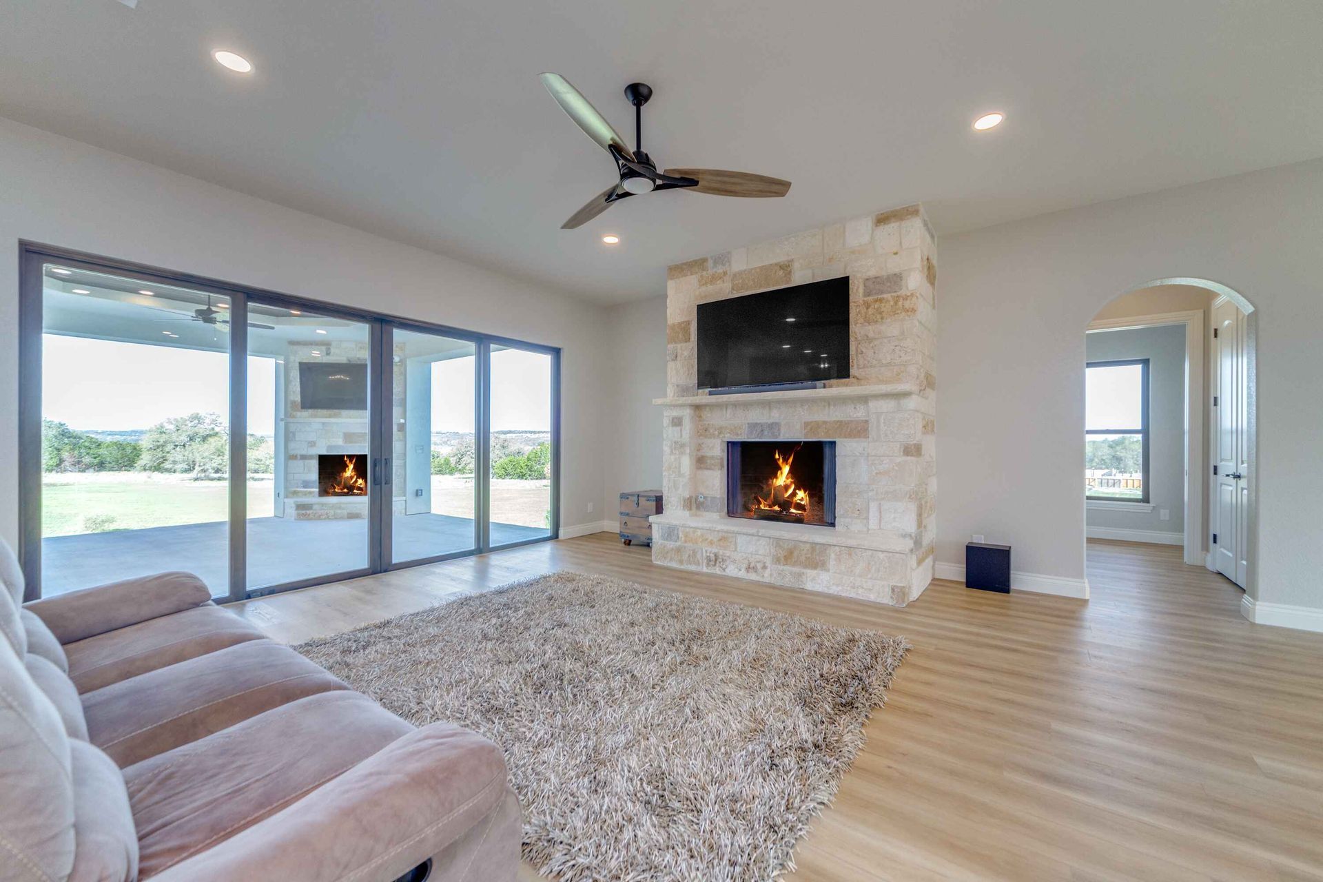 A living room with a fireplace and a ceiling fan.