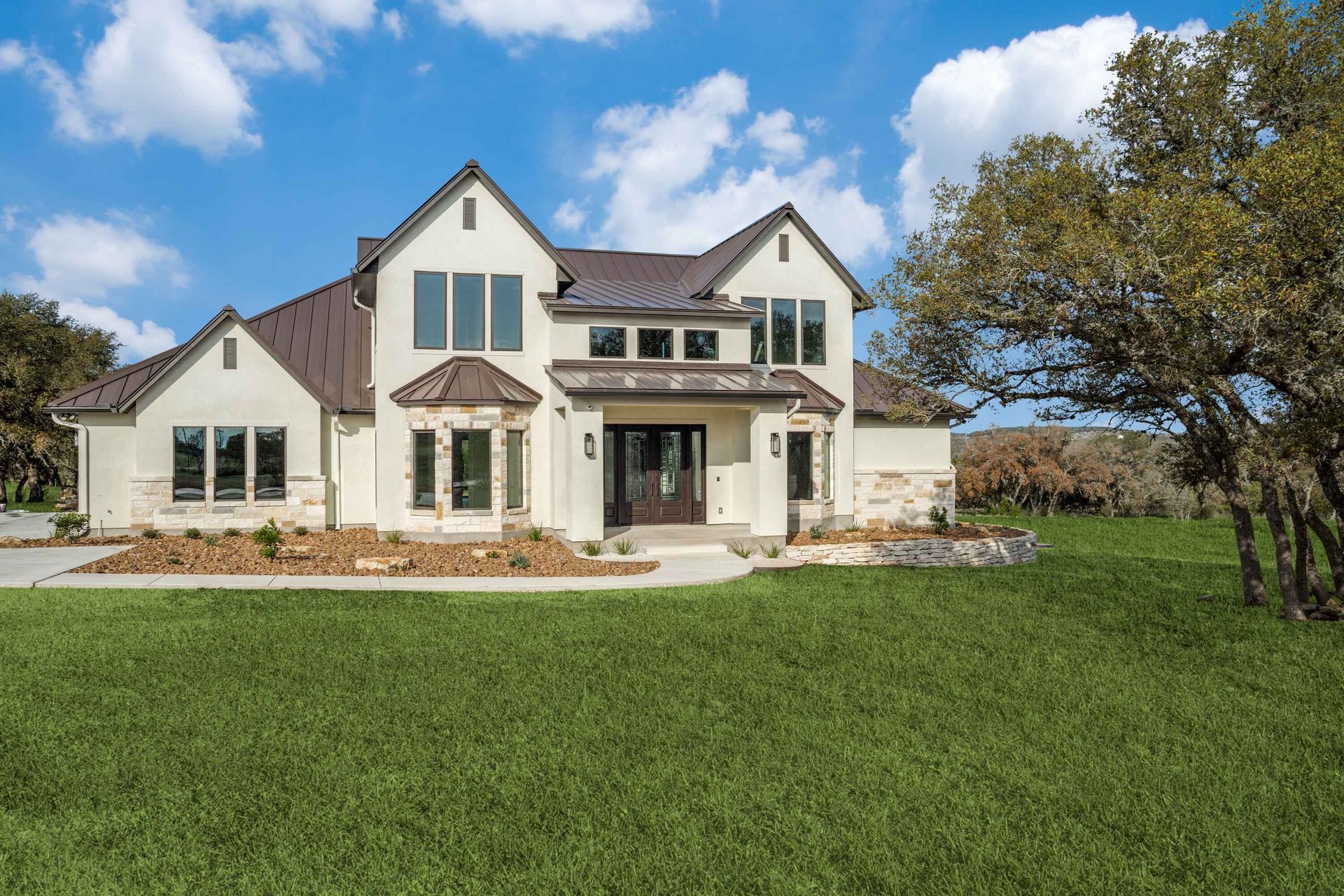 A large white house with a brown roof is sitting on top of a lush green field.