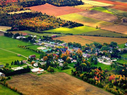 Vue aérienne d'un village rural entouré de champs en mosaïque aux couleurs d'automne