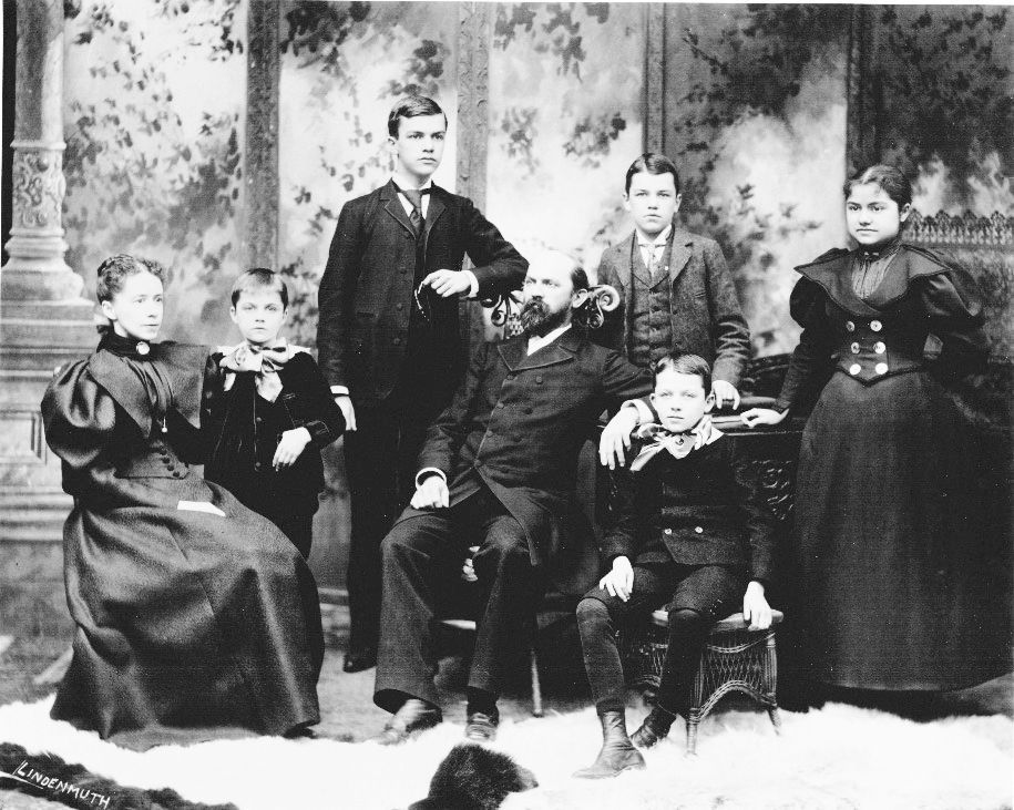 Formal black-and-white family portrait with six people posed against a painted backdrop.