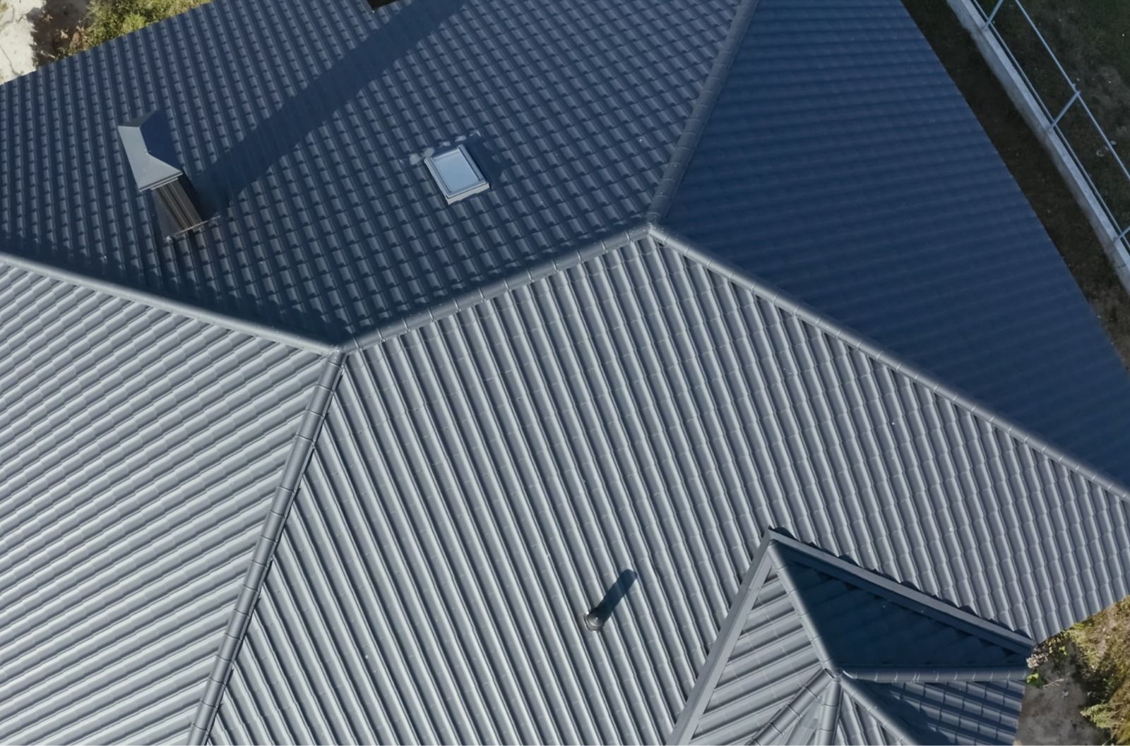Vista aérea del techo de una casa con paneles metálicos de color gris oscuro y gris claro.