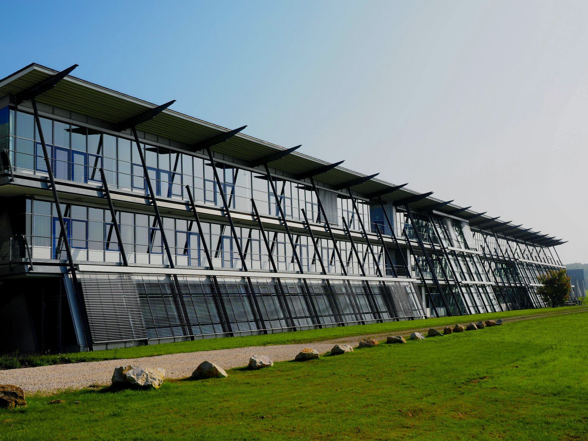 A large building with a lot of windows is surrounded by grass and rocks