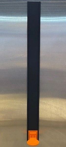 Black rectangular object with an orange base against a silver metal background.
