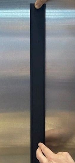 A person holding a long, black strip against a stainless steel surface.