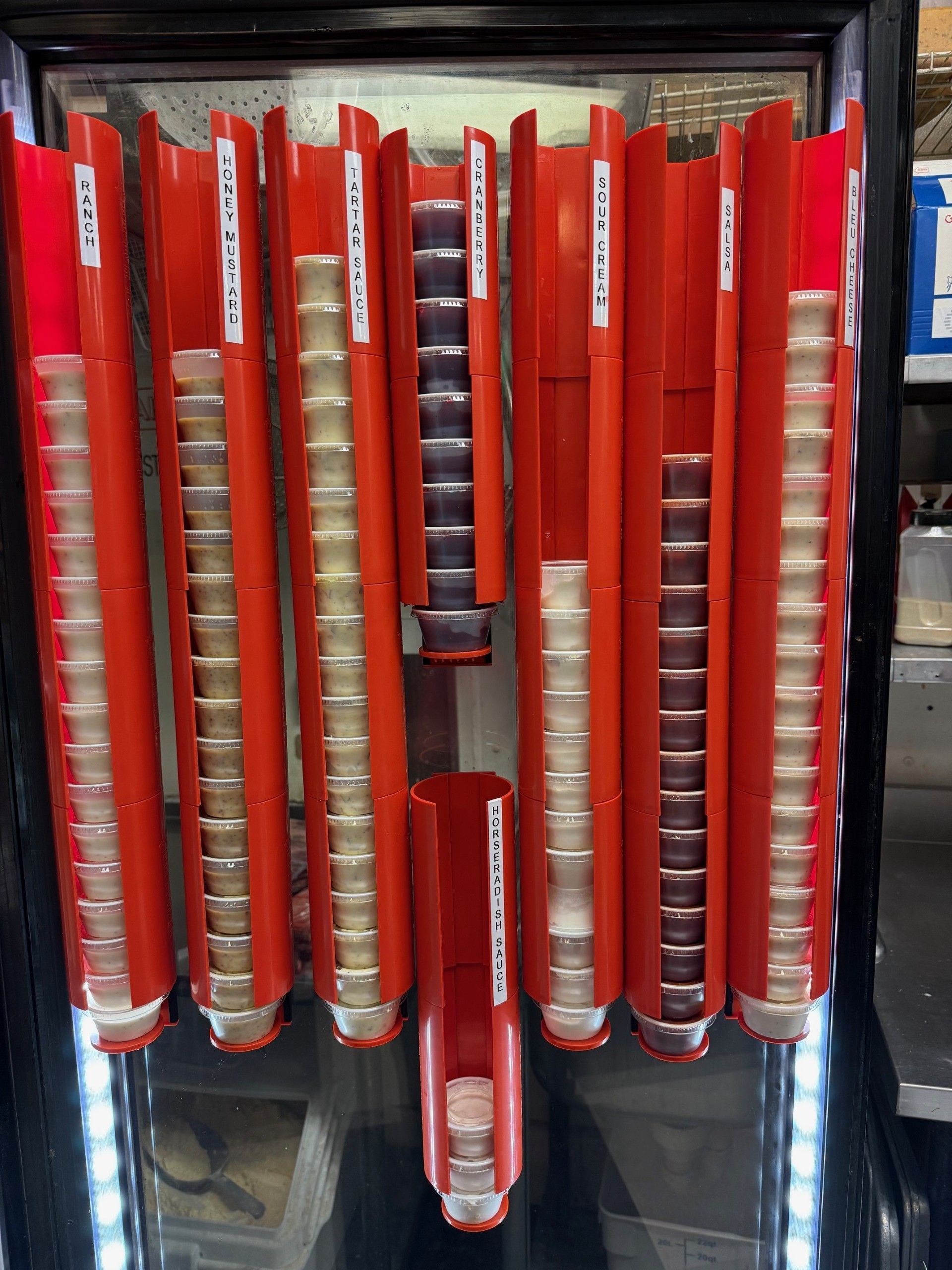 Red cup dispenser with rows of stacked clear cups.