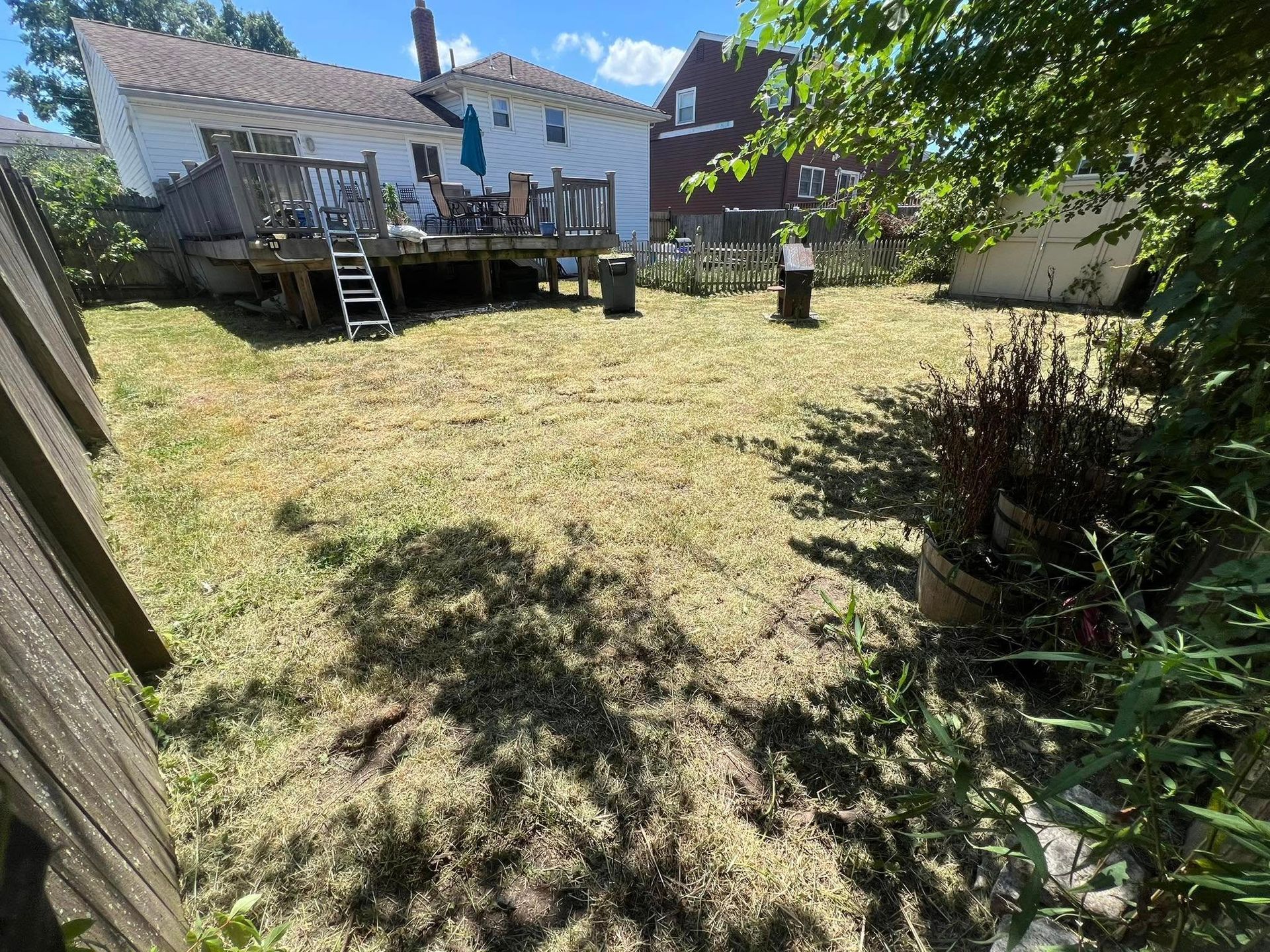 A backyard with a deck and a house in the background.