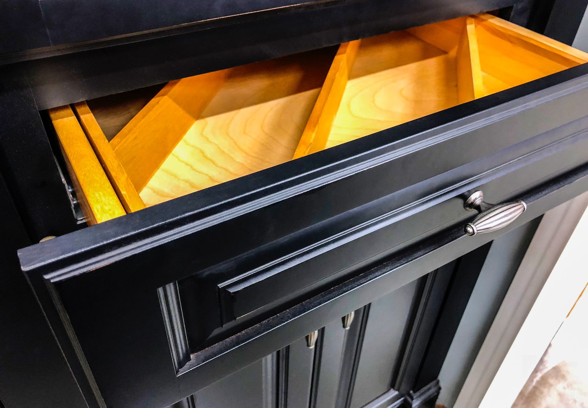 Black bathroom cabinet with open drawer, revealing a wooden organizer.