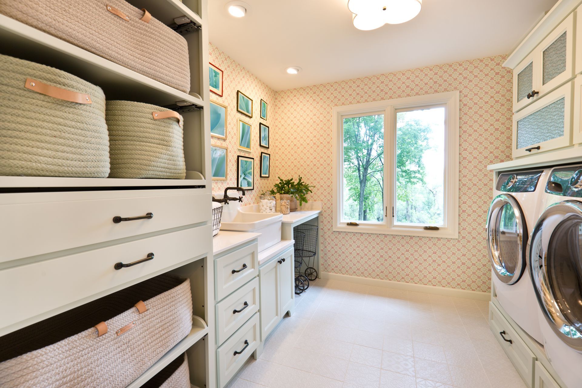 Laundry room with white cabinets, washer, dryer, woven baskets, and a window.