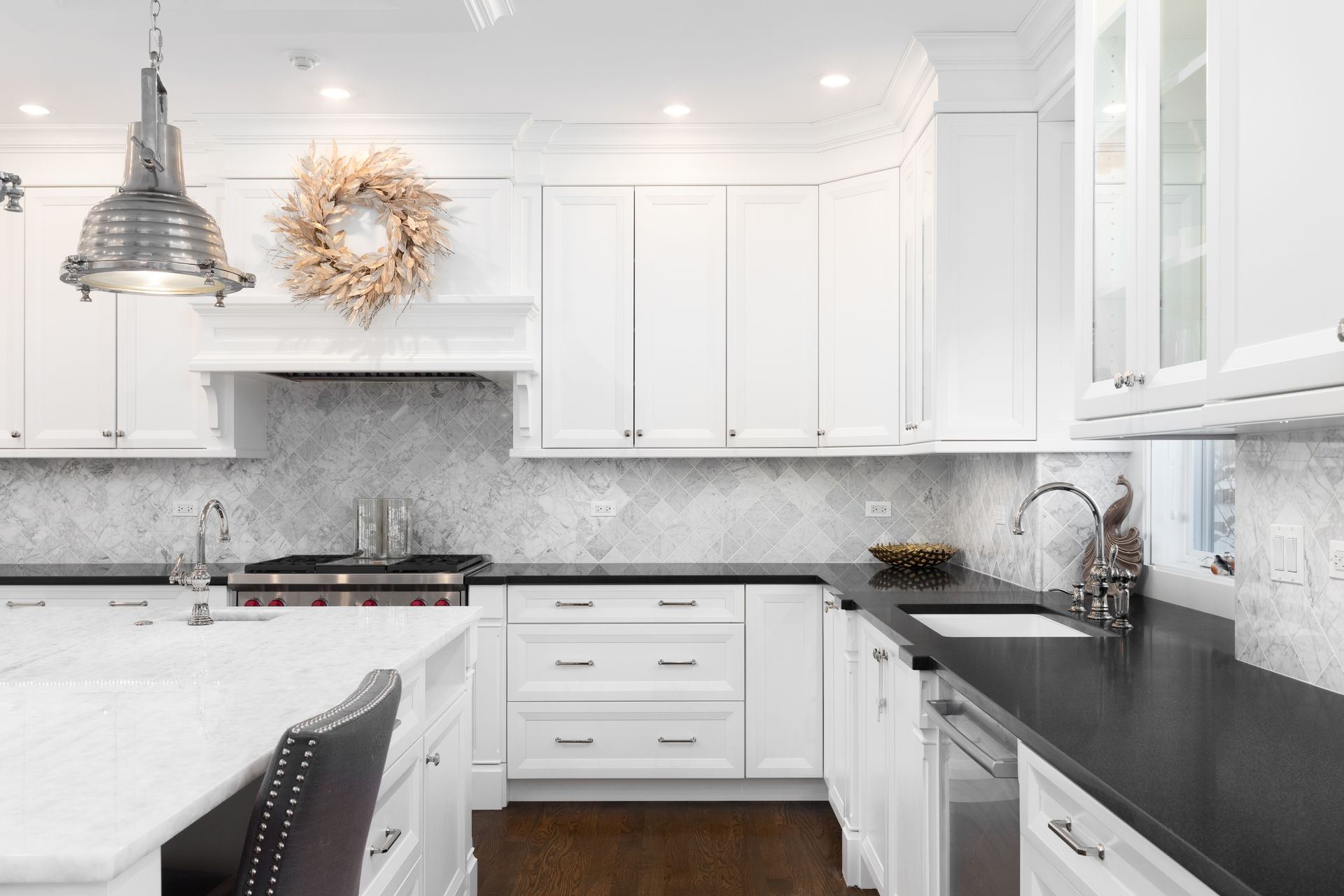 White kitchen with marble countertops, white cabinets, and a wreath above the stove.